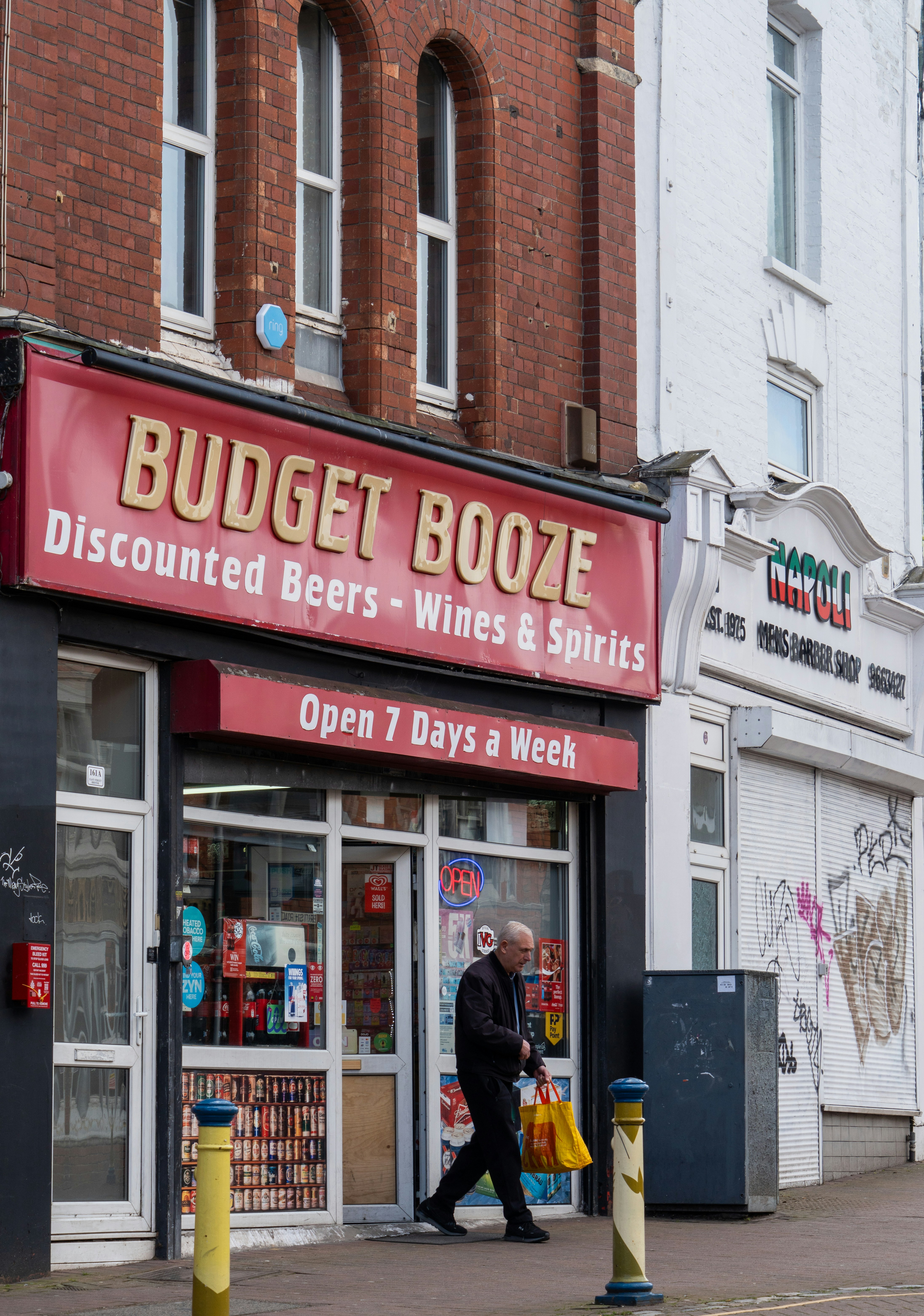 Man walks past a "budget booze" shop