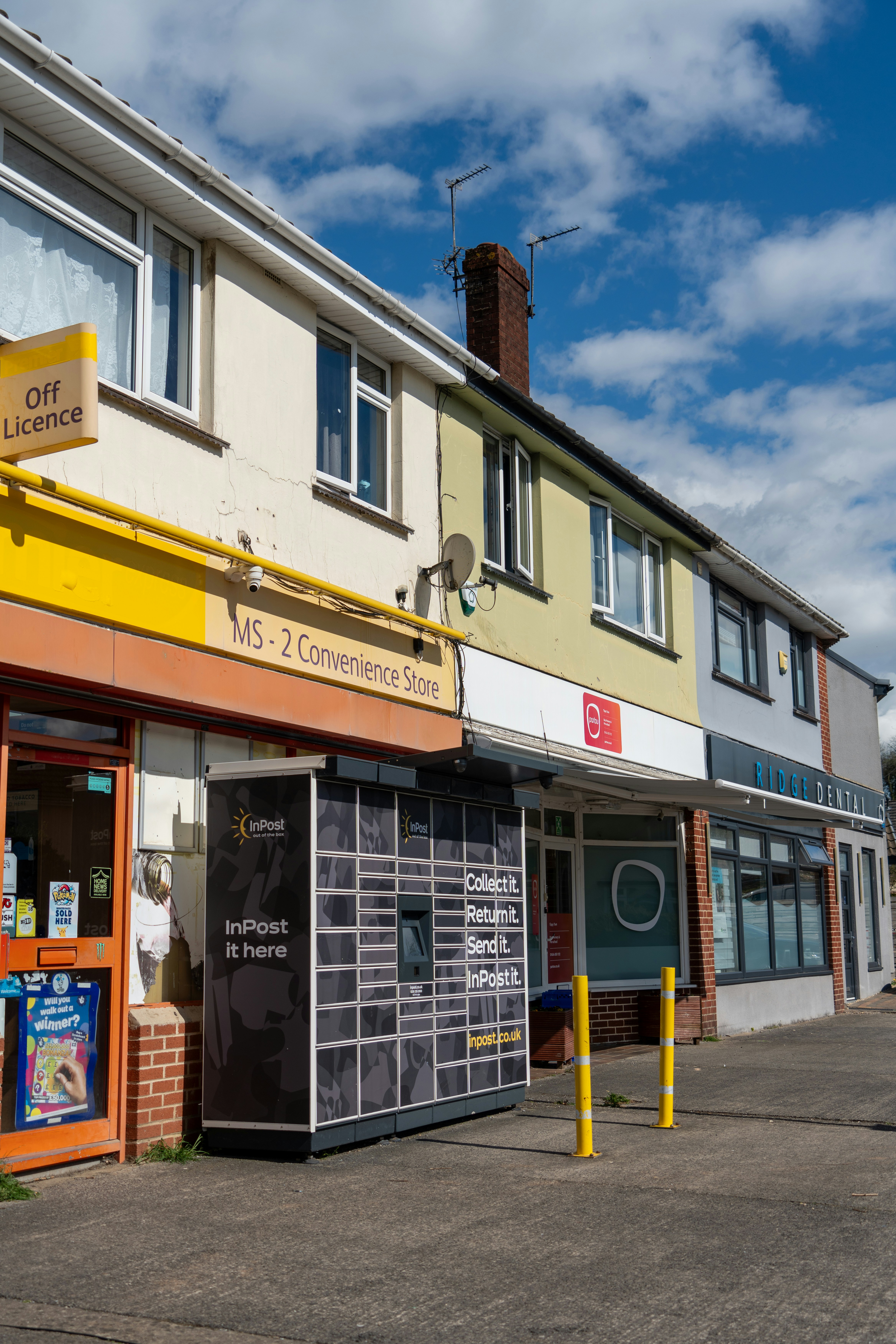 Row of shops with a parcel locker outside.