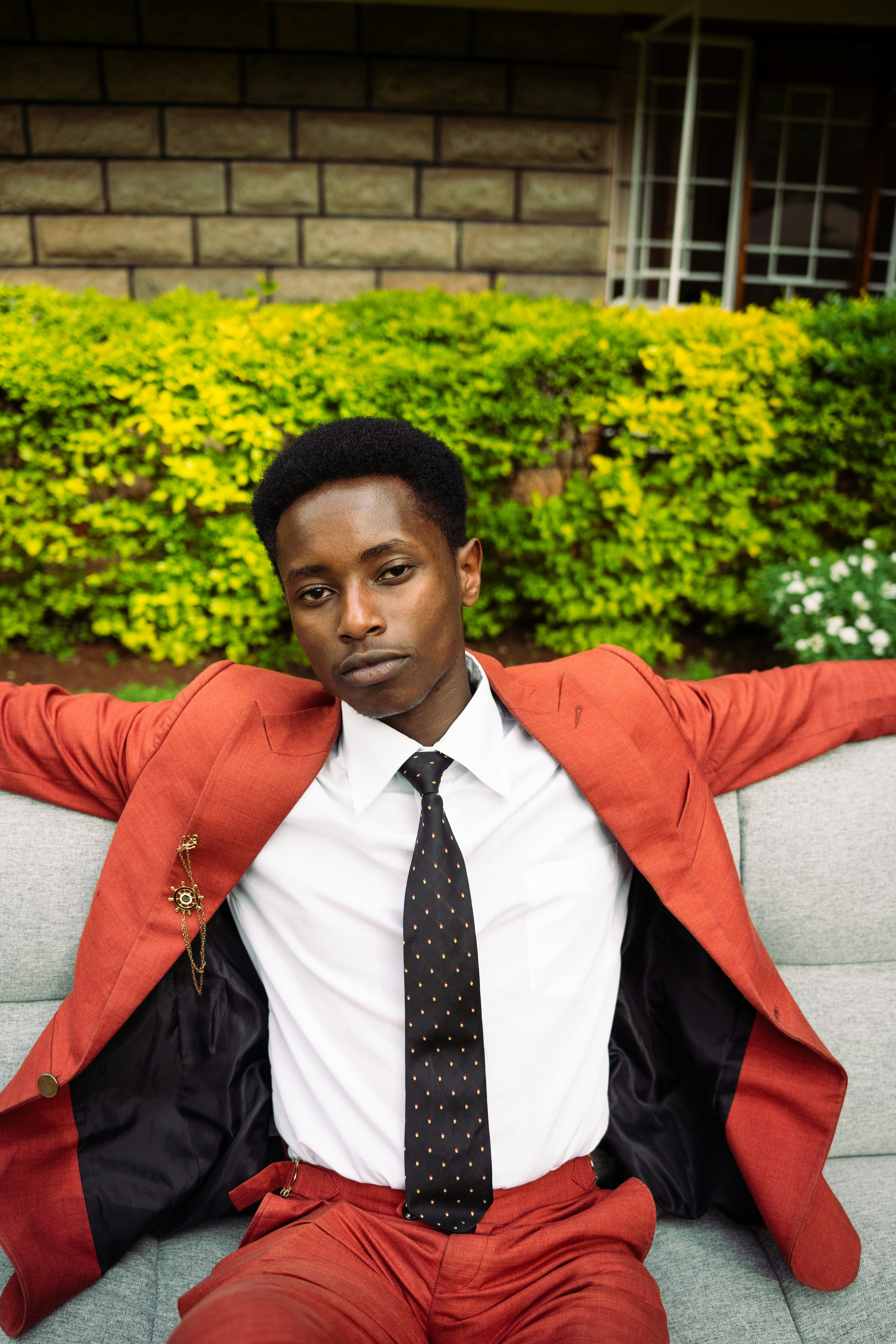 A young man in a suit sits on a couch.