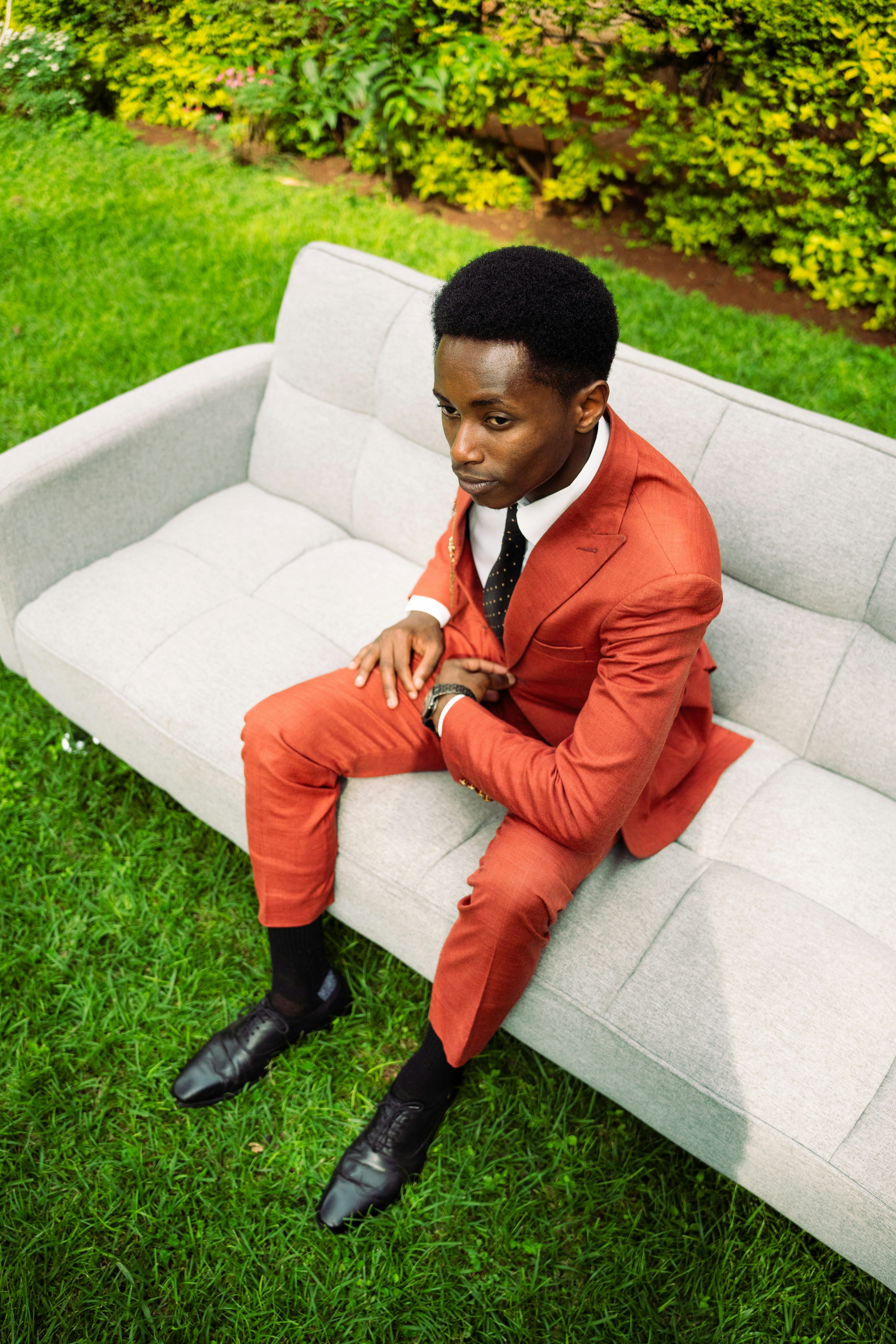 Homme en costume orange assis sur un canapé extérieur