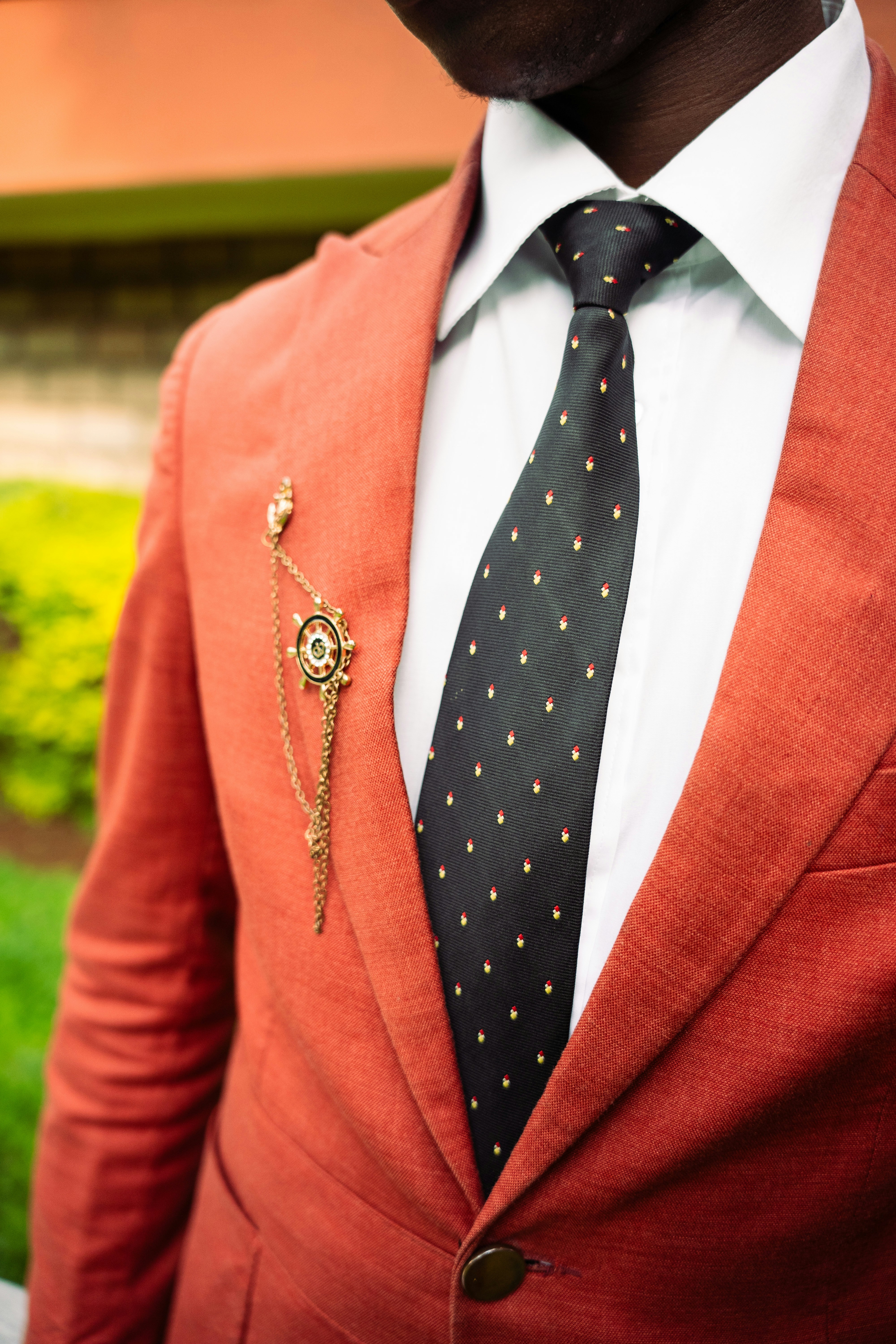Homem de terno laranja com gravata e broche de bolinhas