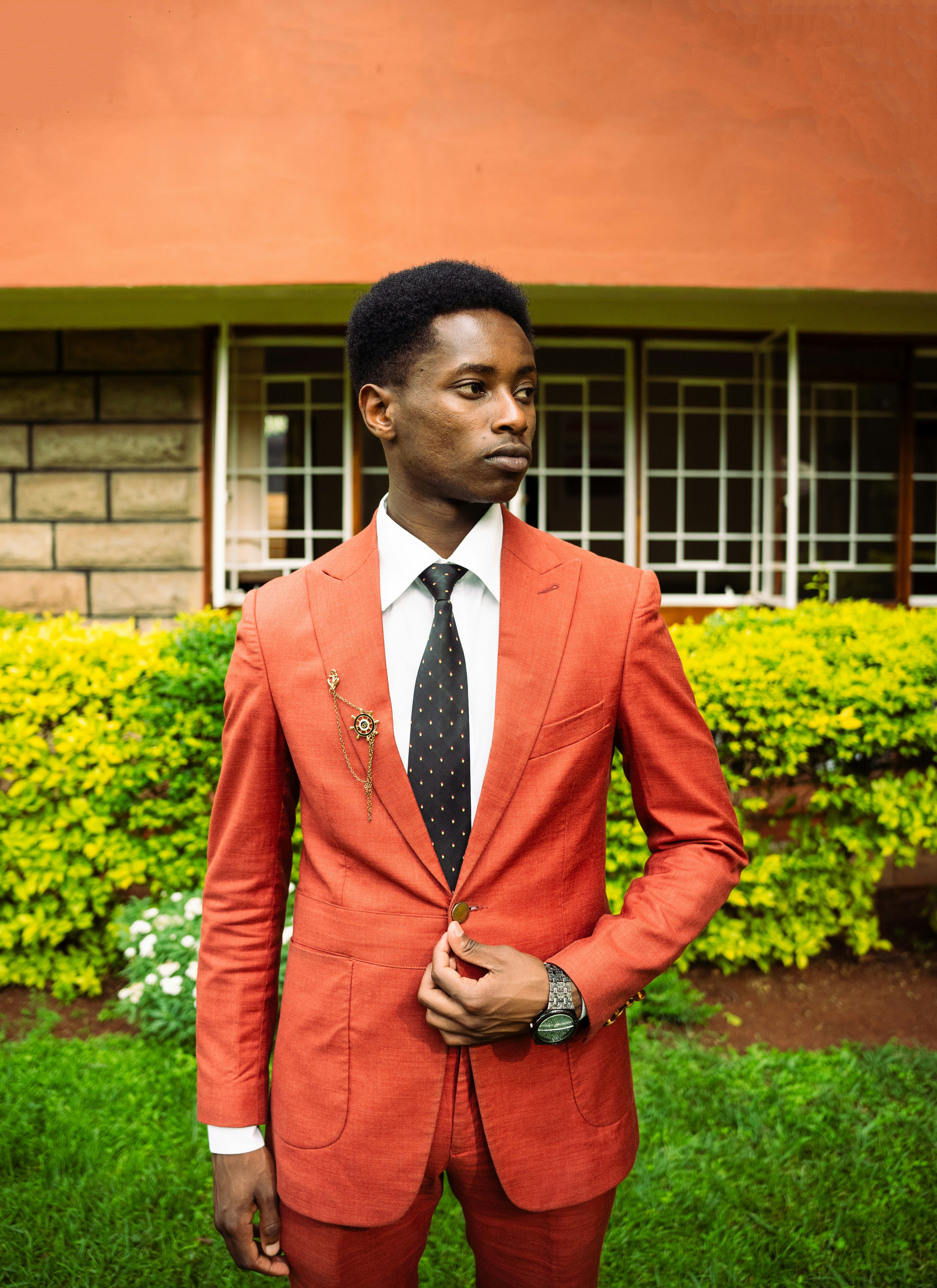 Seorang pria muda berjas merah berdiri di luar ruangan.