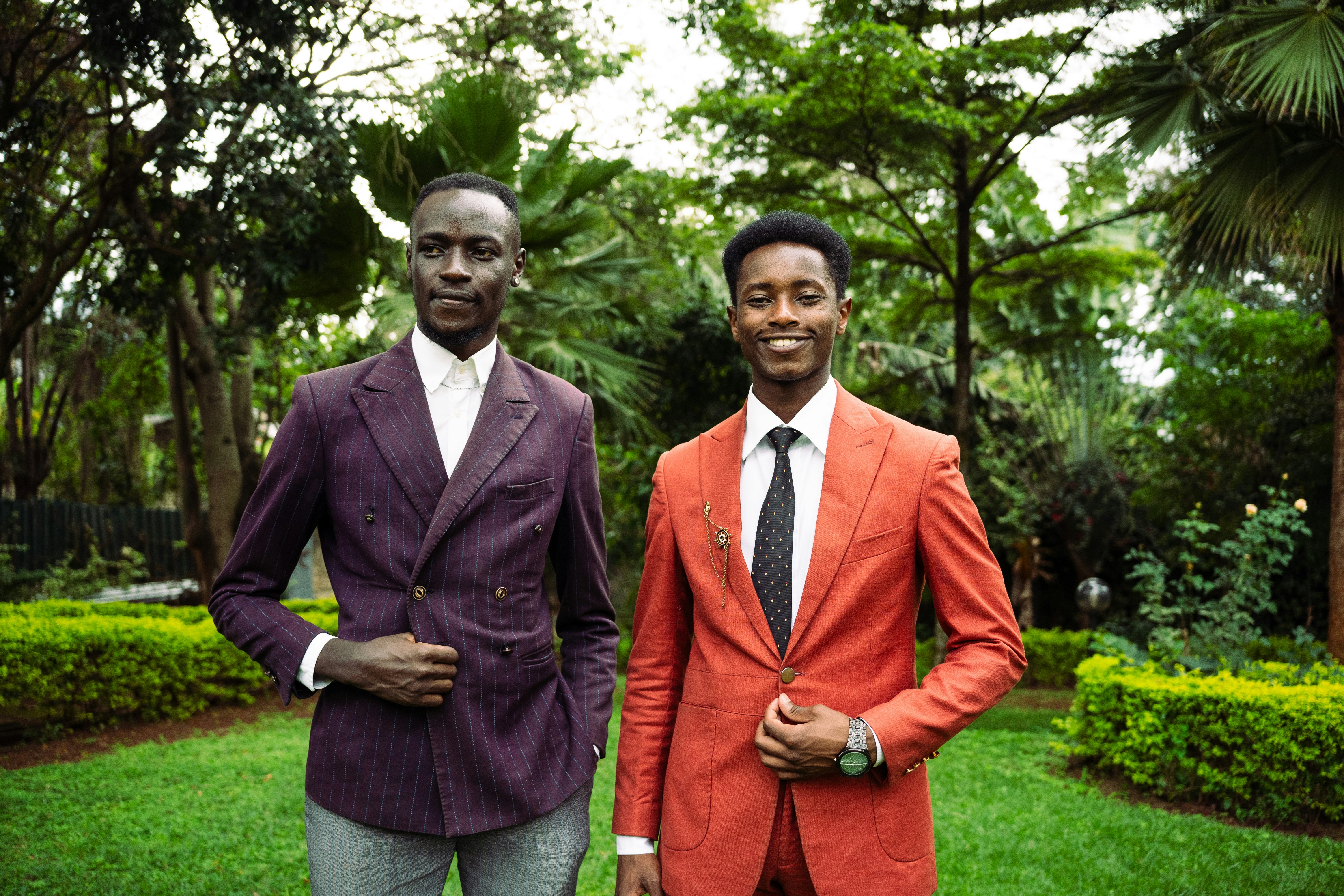 Dos hombres con traje de pie en un jardín