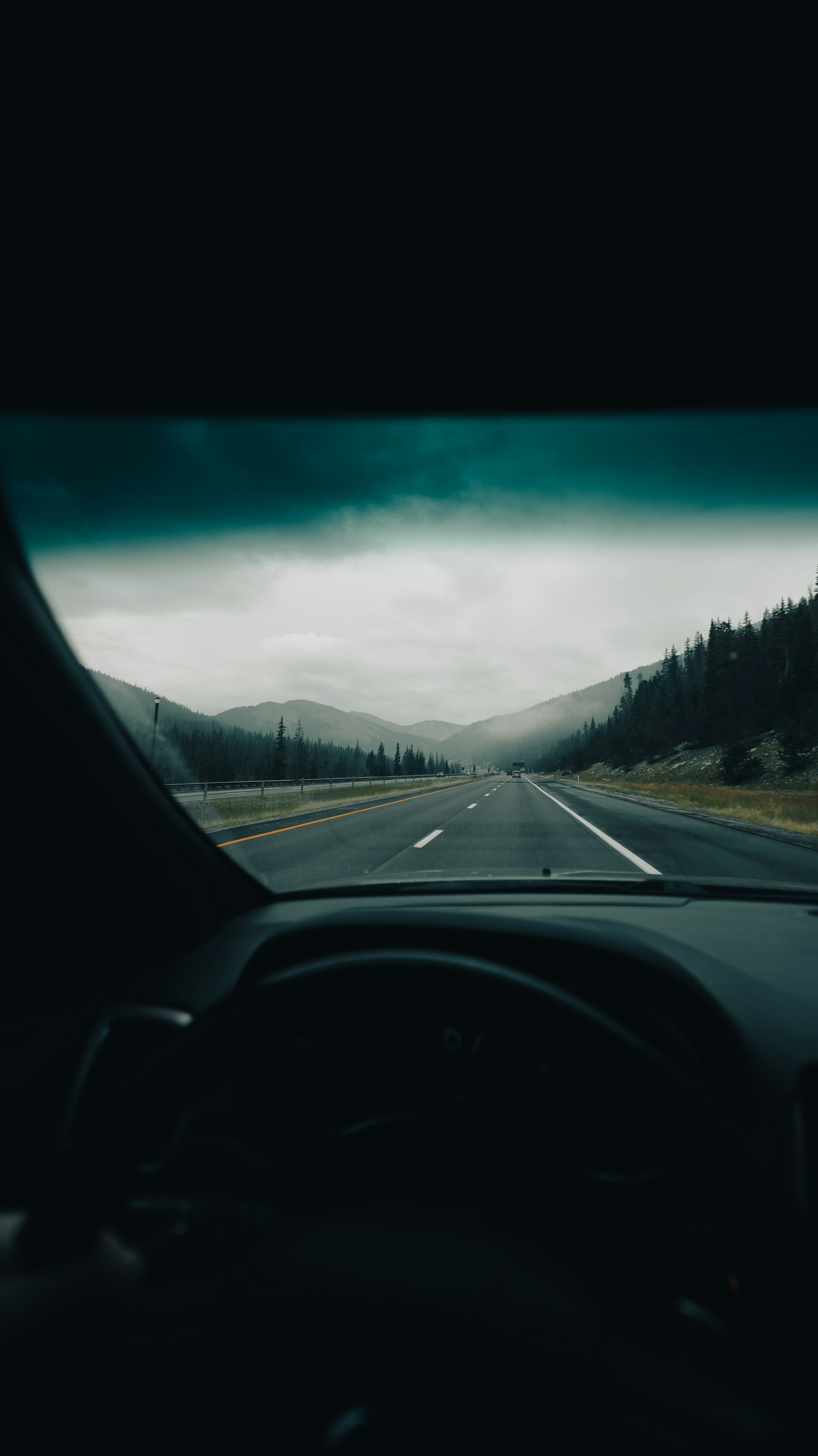 Auf einer Autobahn durch Berge an einem bewölkten Tag fahren.