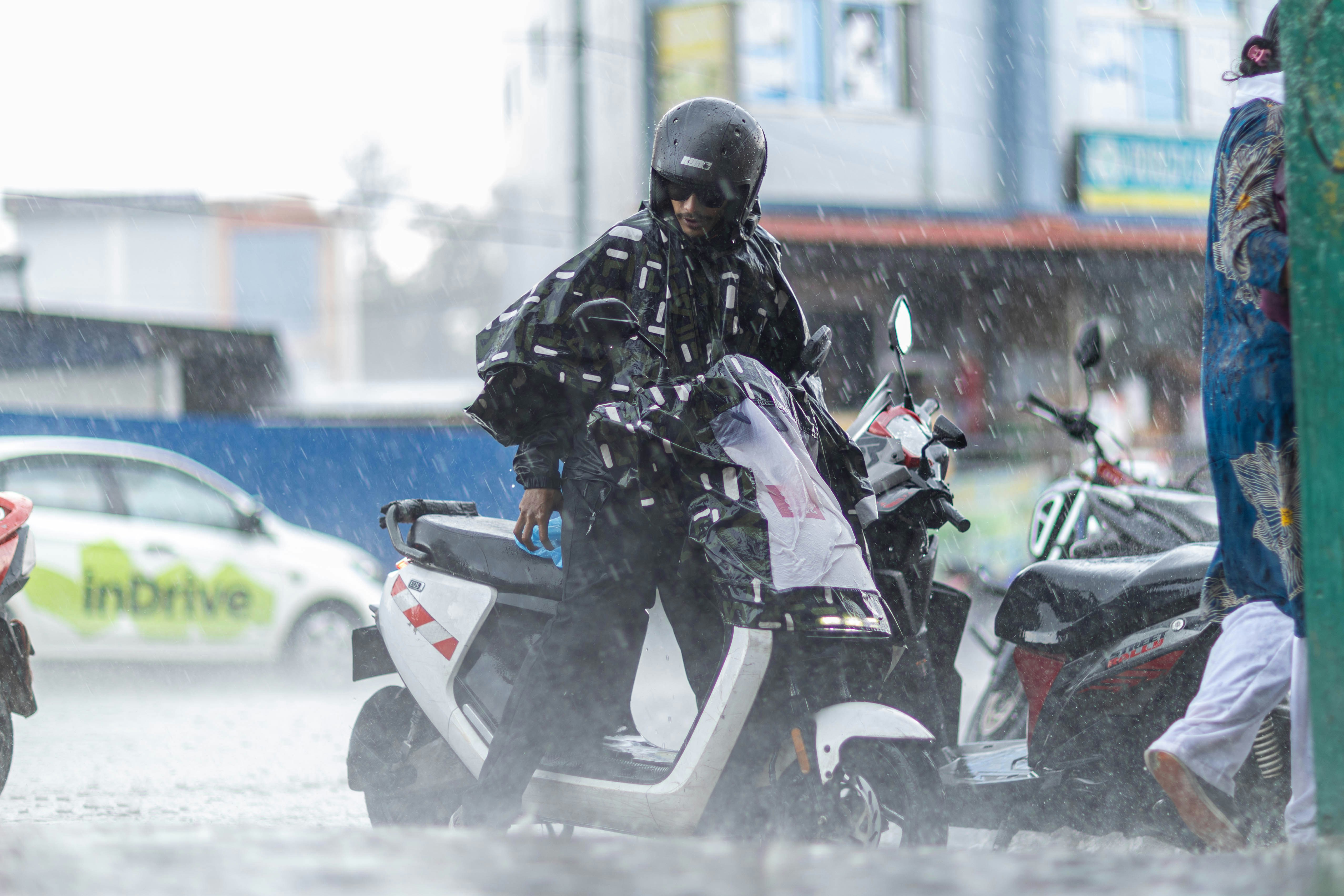 激しい雨の中でスクーターに乗っている人