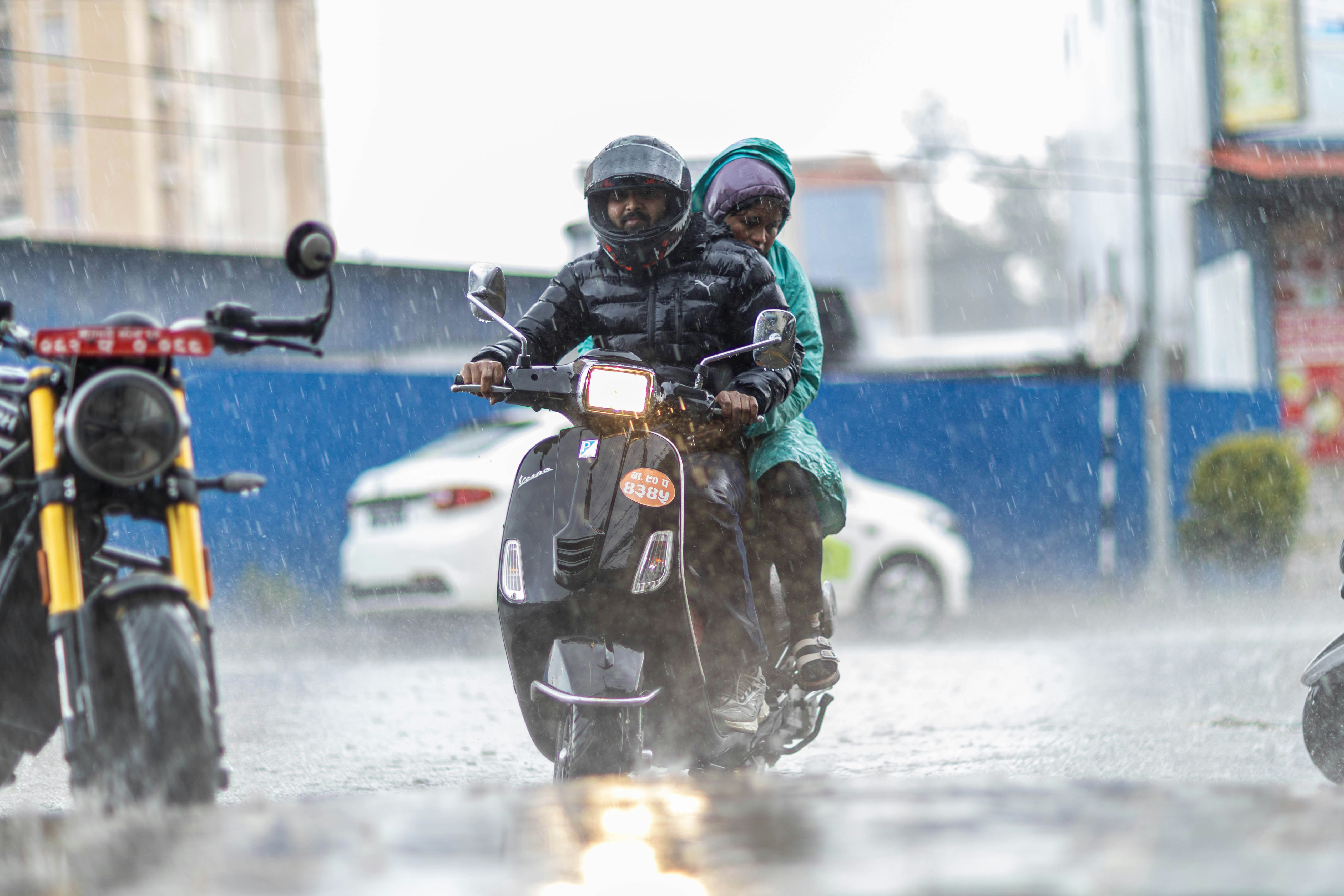 雨の中でスクーターに乗る二人。