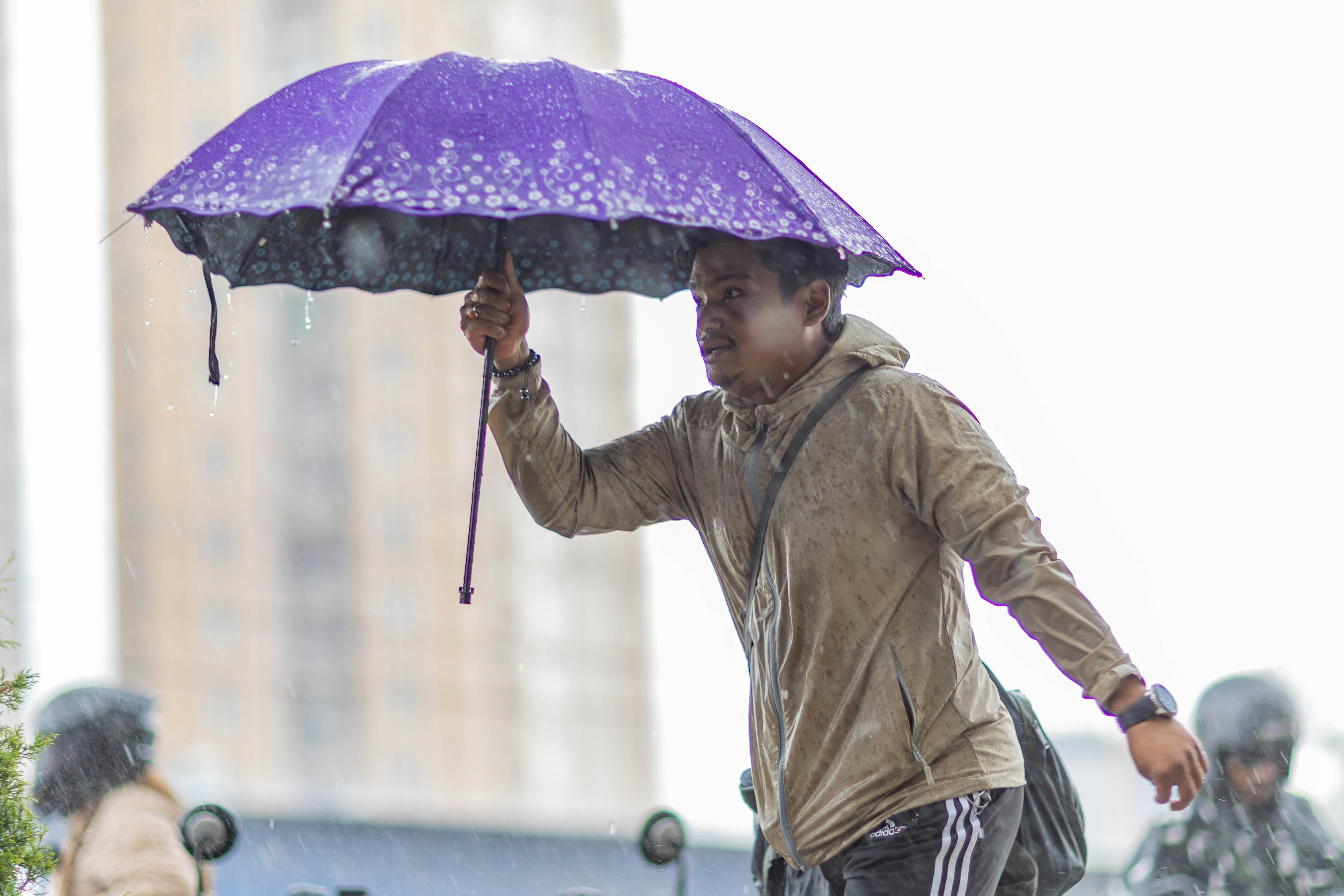 雨の中で紫色の傘を持った人。