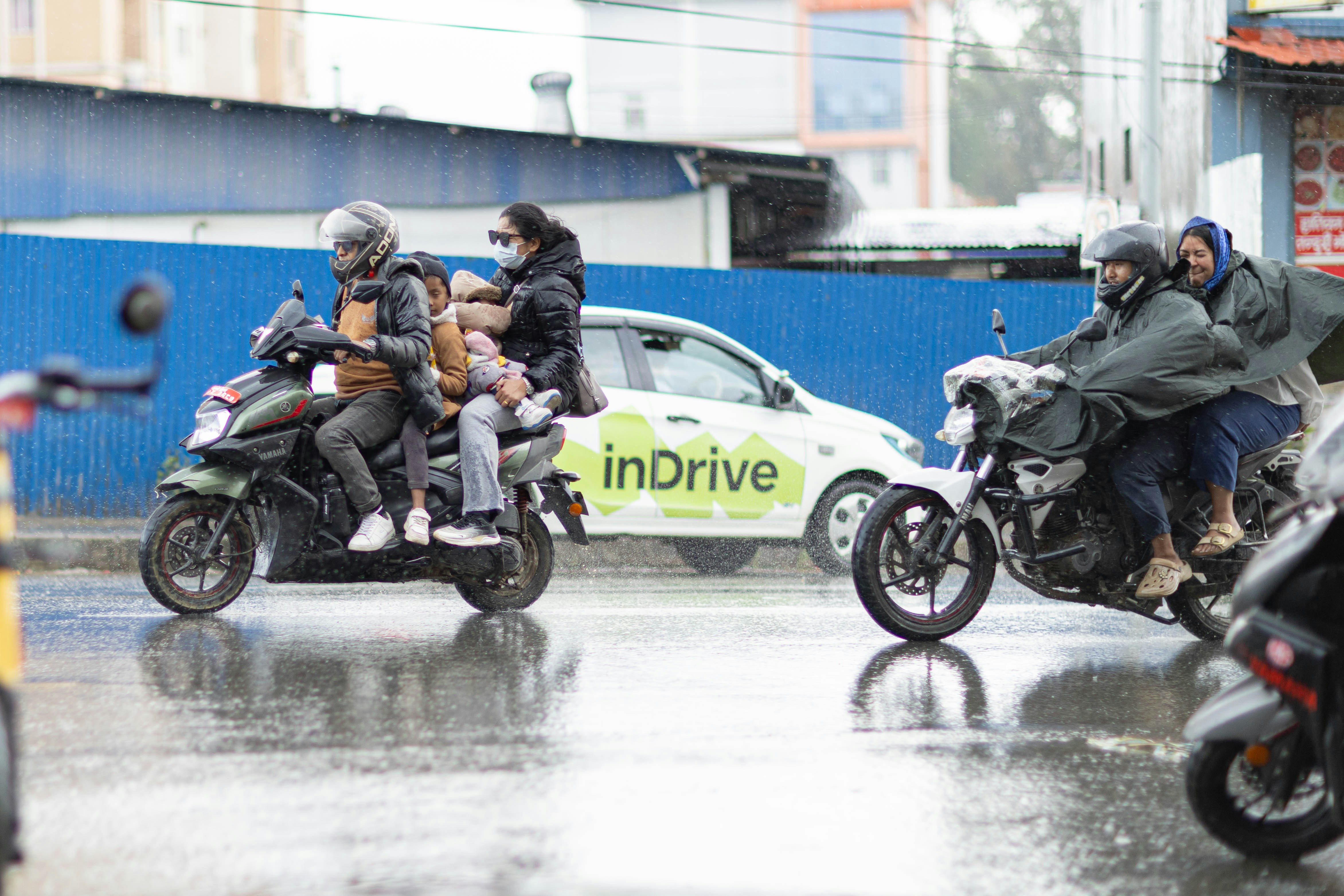雨の中、濡れた市街地をバイク乗りが走っています。