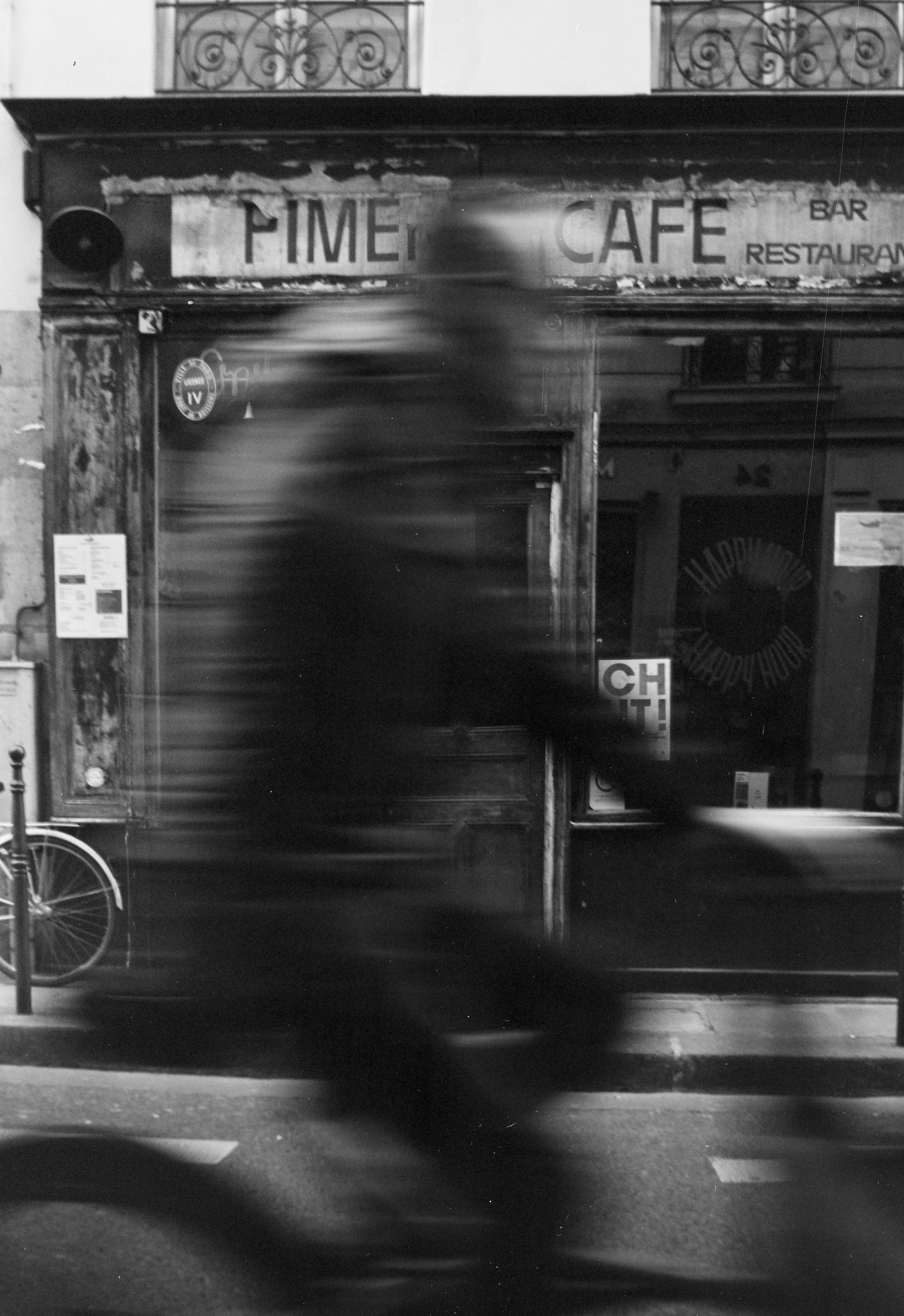 Figura borrada em bicicleta passa, vitrine de loja de café