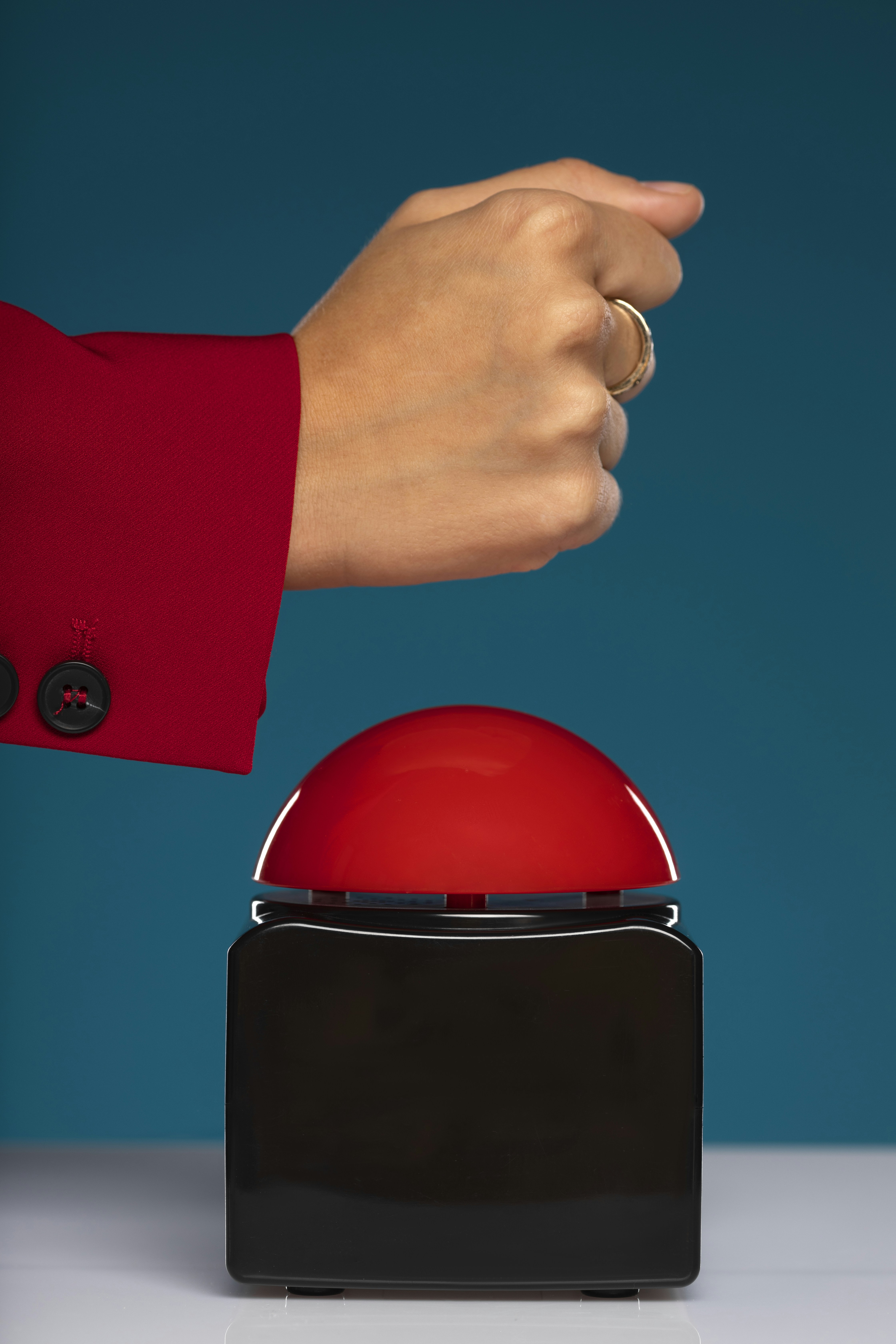 A hand points to a large red button.