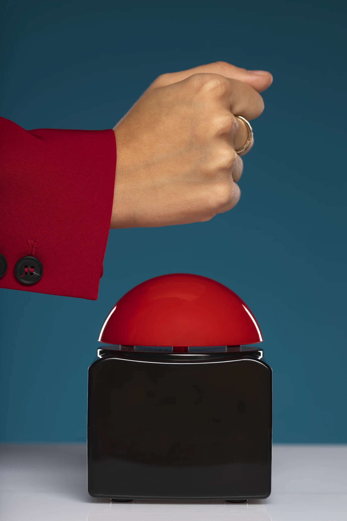 A hand pressing a large red button