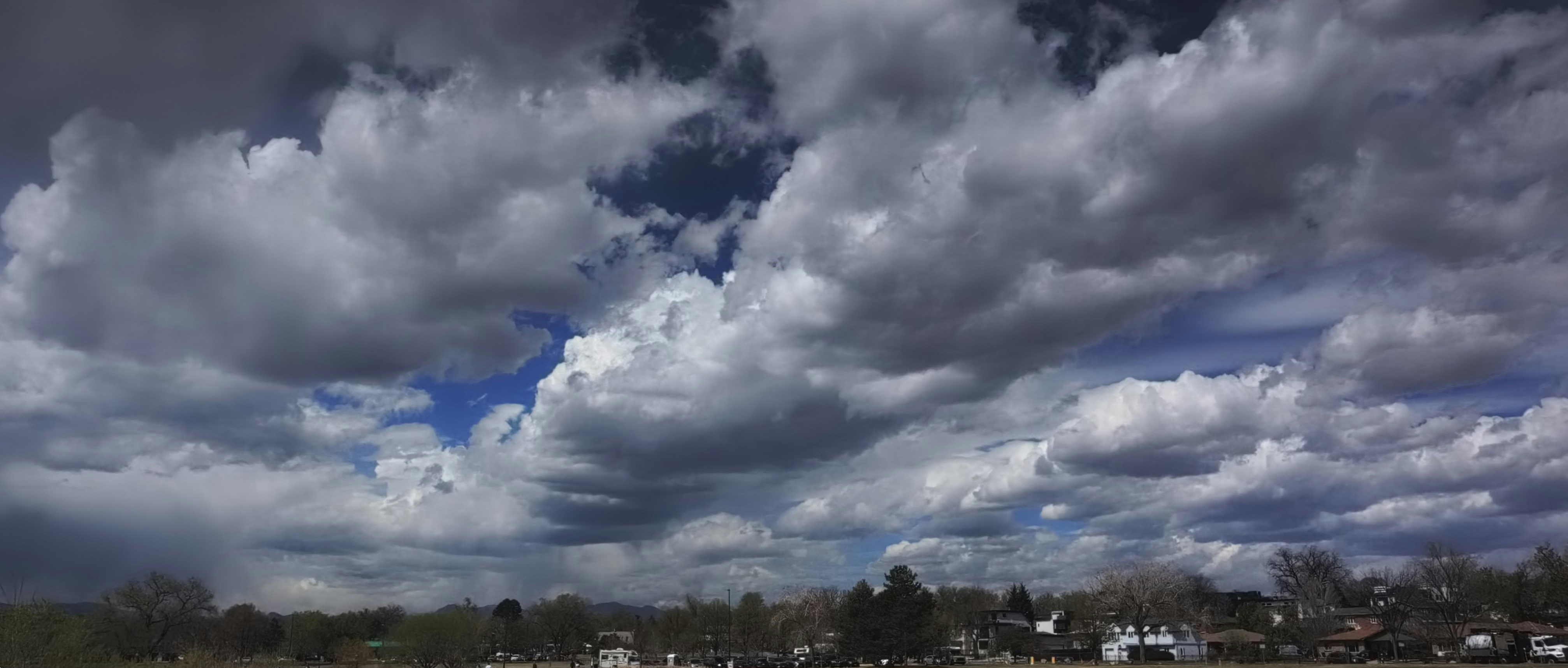 Des nuages spectaculaires emplissent le ciel au-dessus d’une ville lointaine.