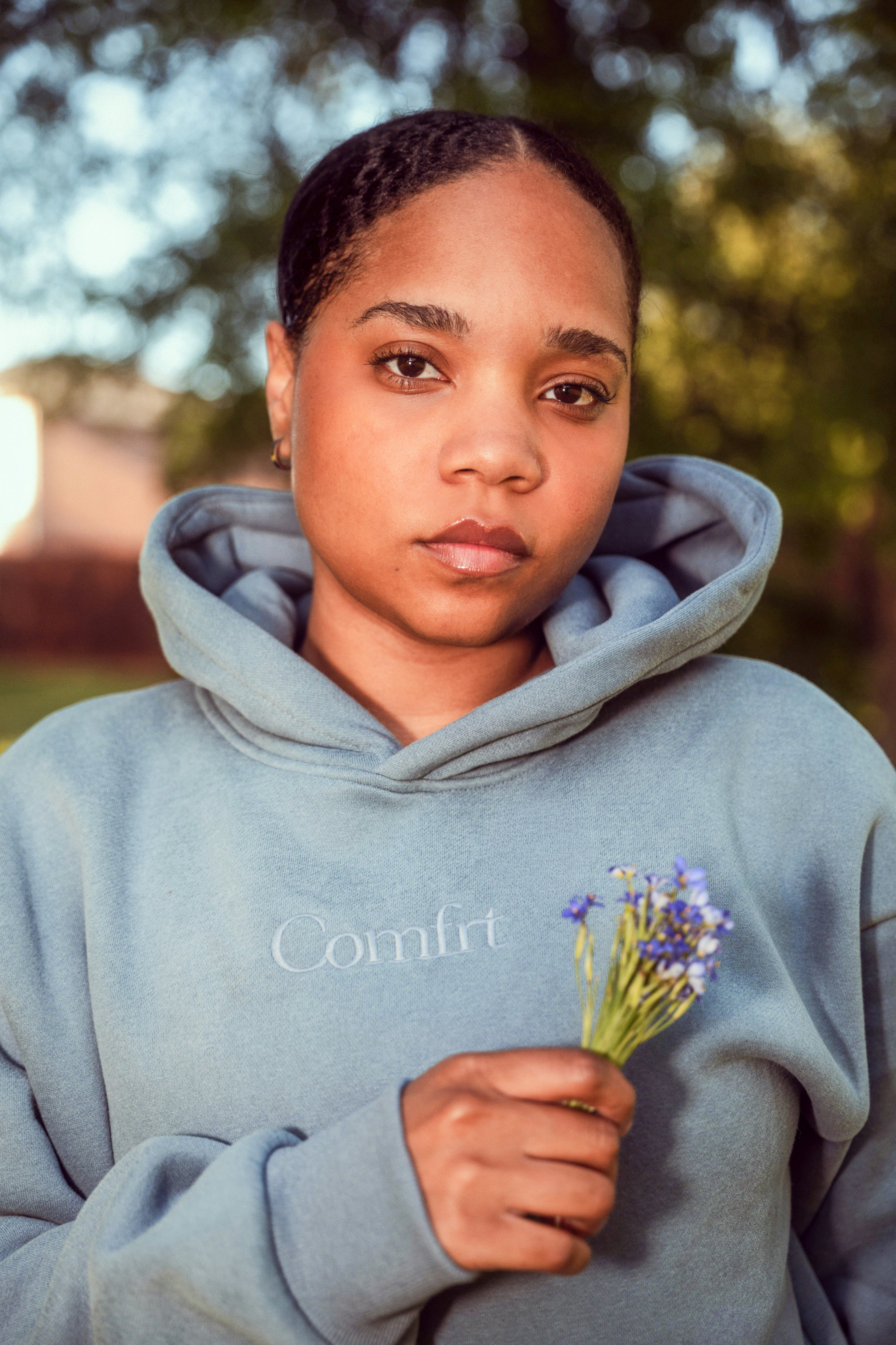 A young woman holds small purple flowers.