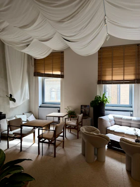 Cozy seating area with tables and chairs under draped ceiling.