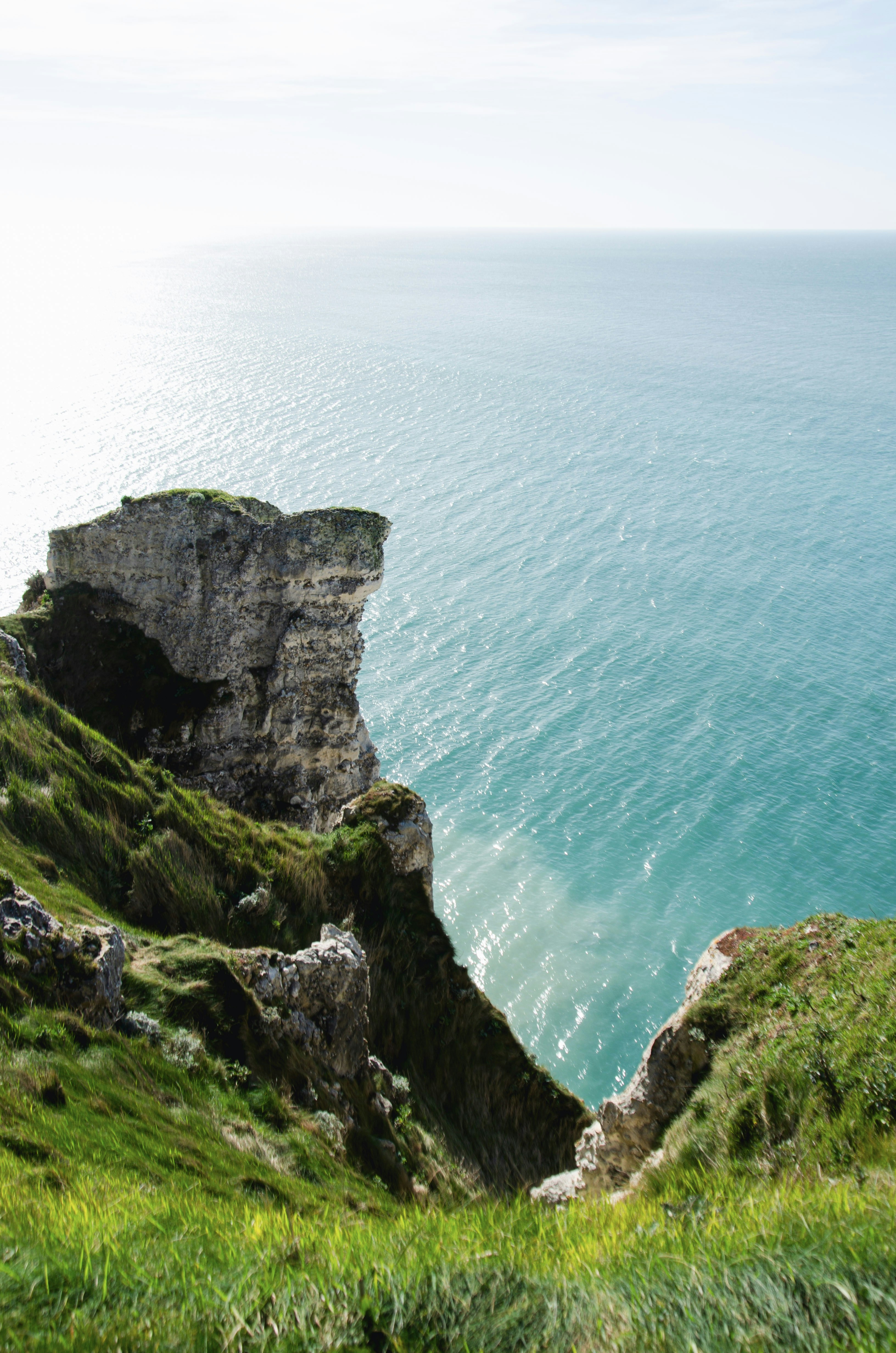Rugged cliffs meet the turquoise ocean under a bright sky