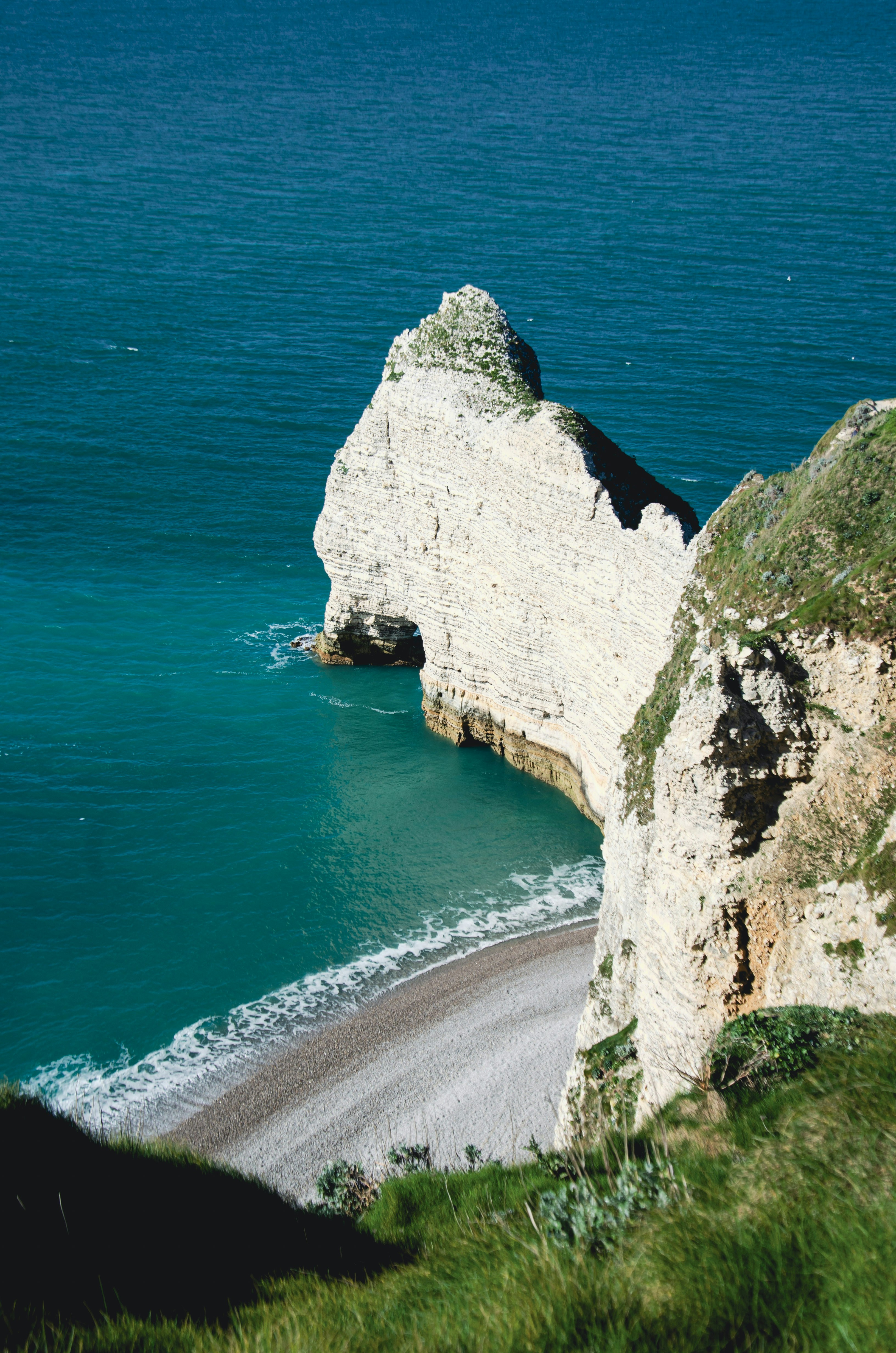White cliffs overlook a turquoise ocean and pebble beach.