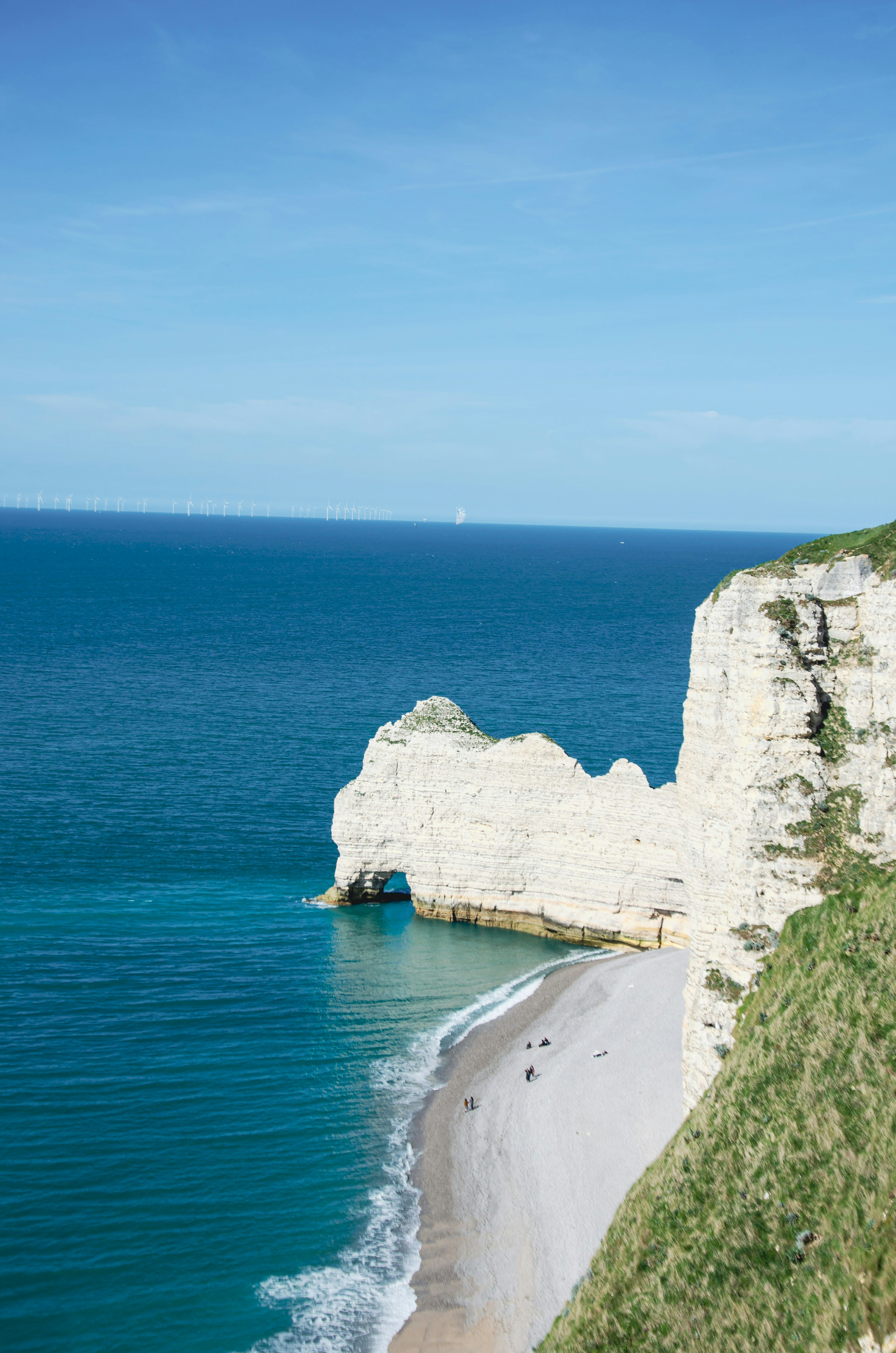 White cliffs and turquoise ocean meet a pebble beach.