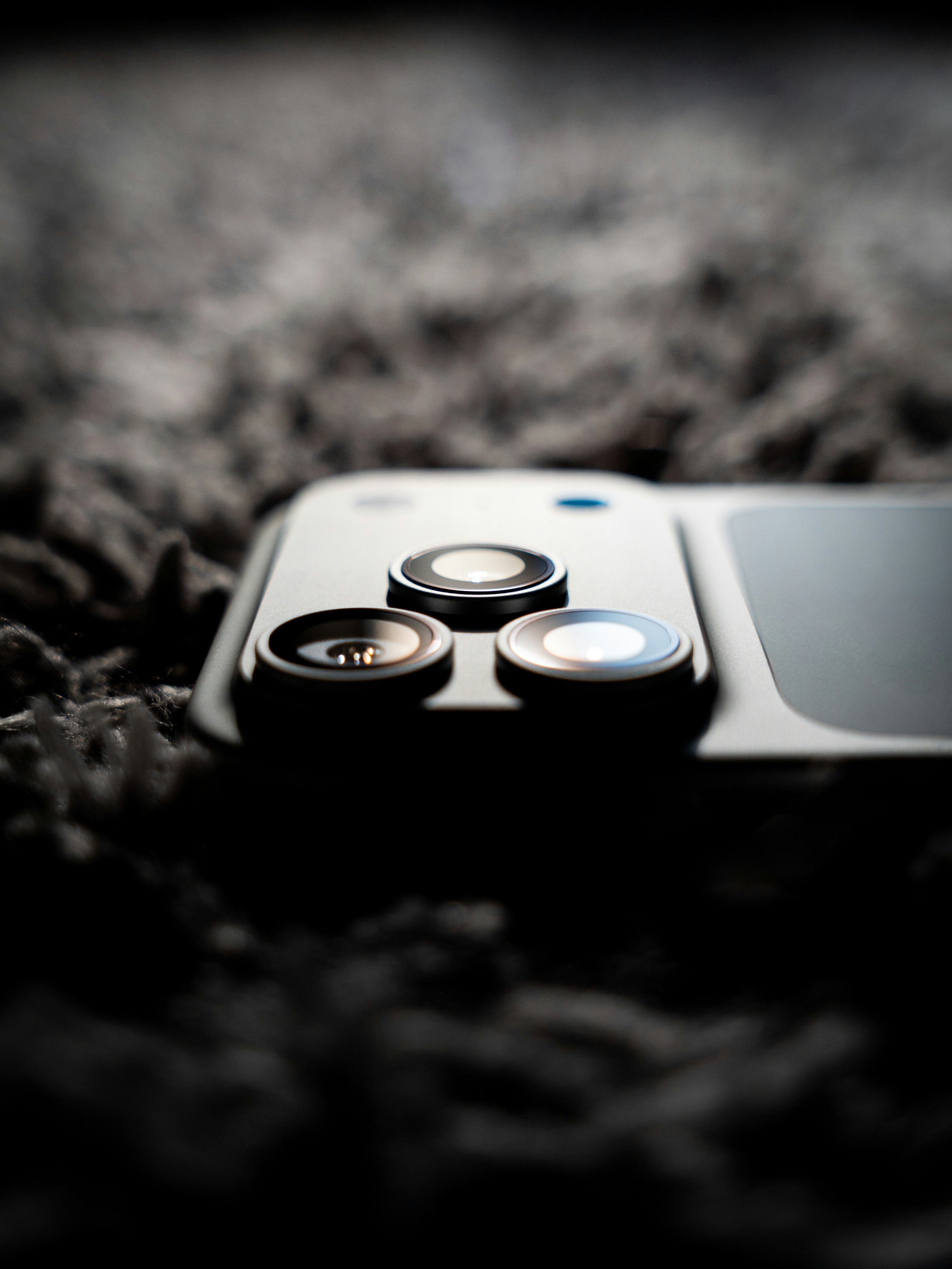 Close-up of a smartphone camera lens array on textured surface