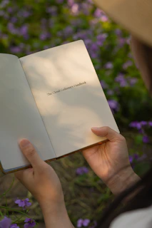 Person holding an open book with purple flowers