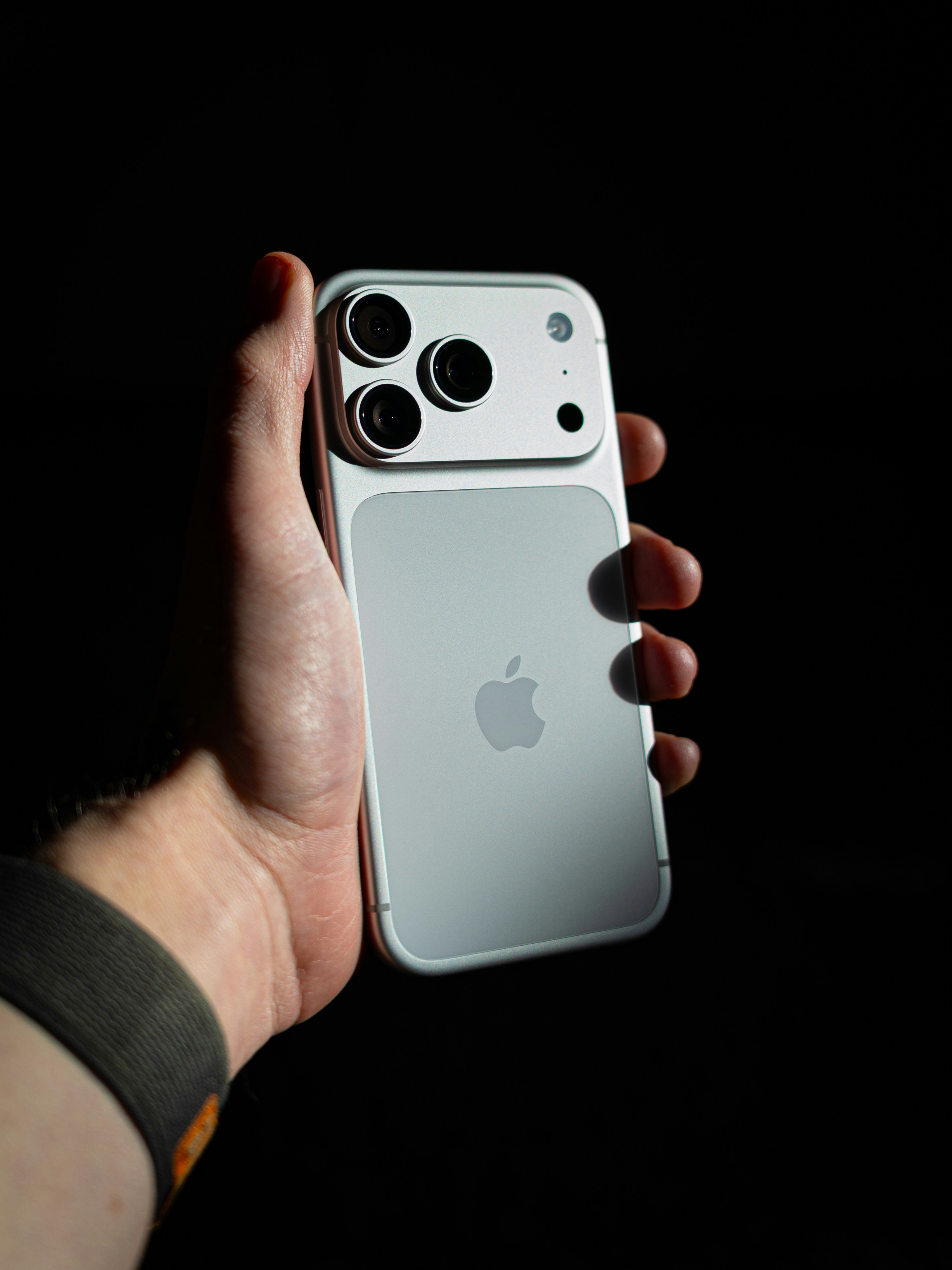 Hand holding a white smartphone with multiple cameras.