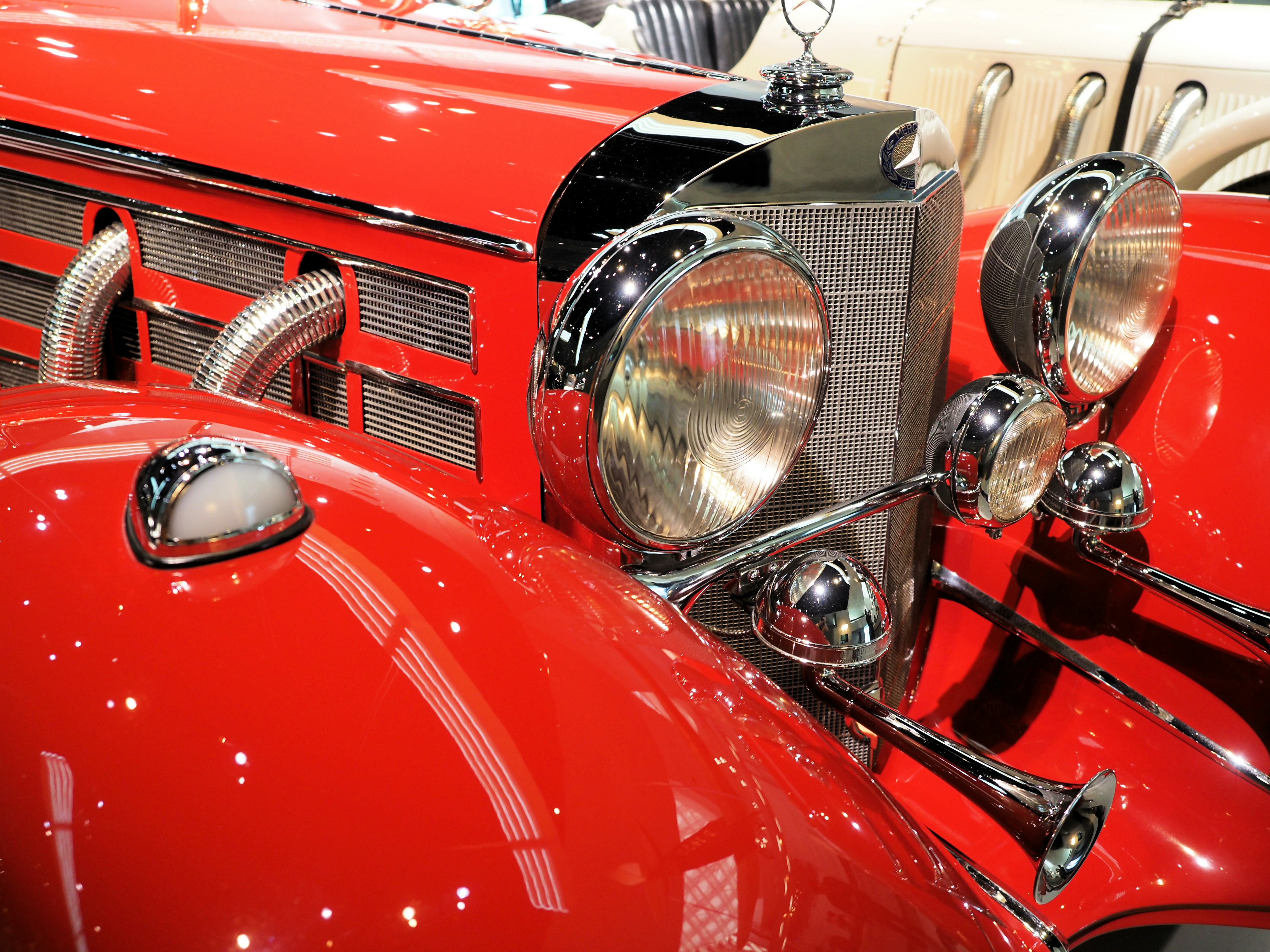 Close-up of a vintage red car's headlights and grille.