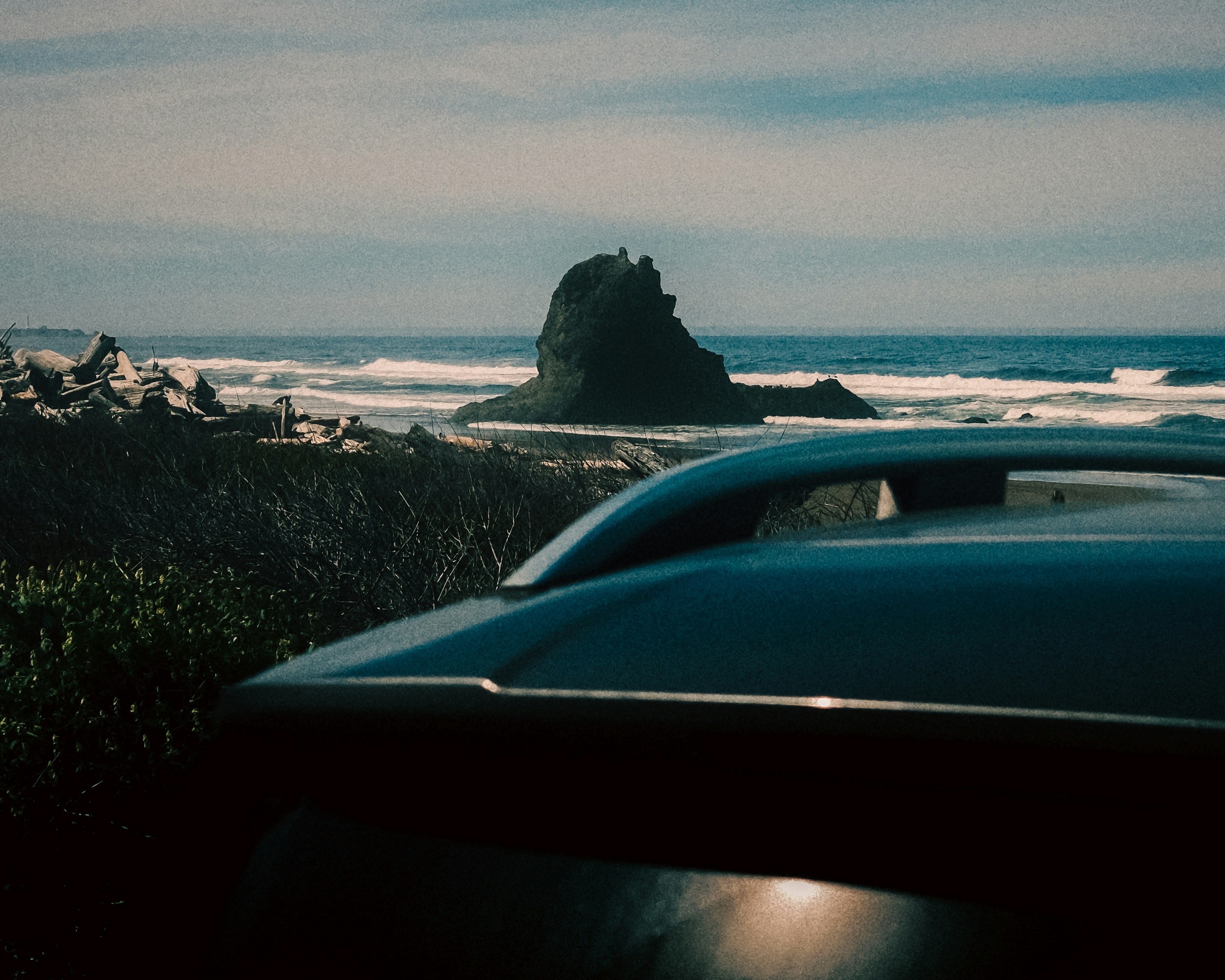 Car parked near rocky coastline and ocean waves