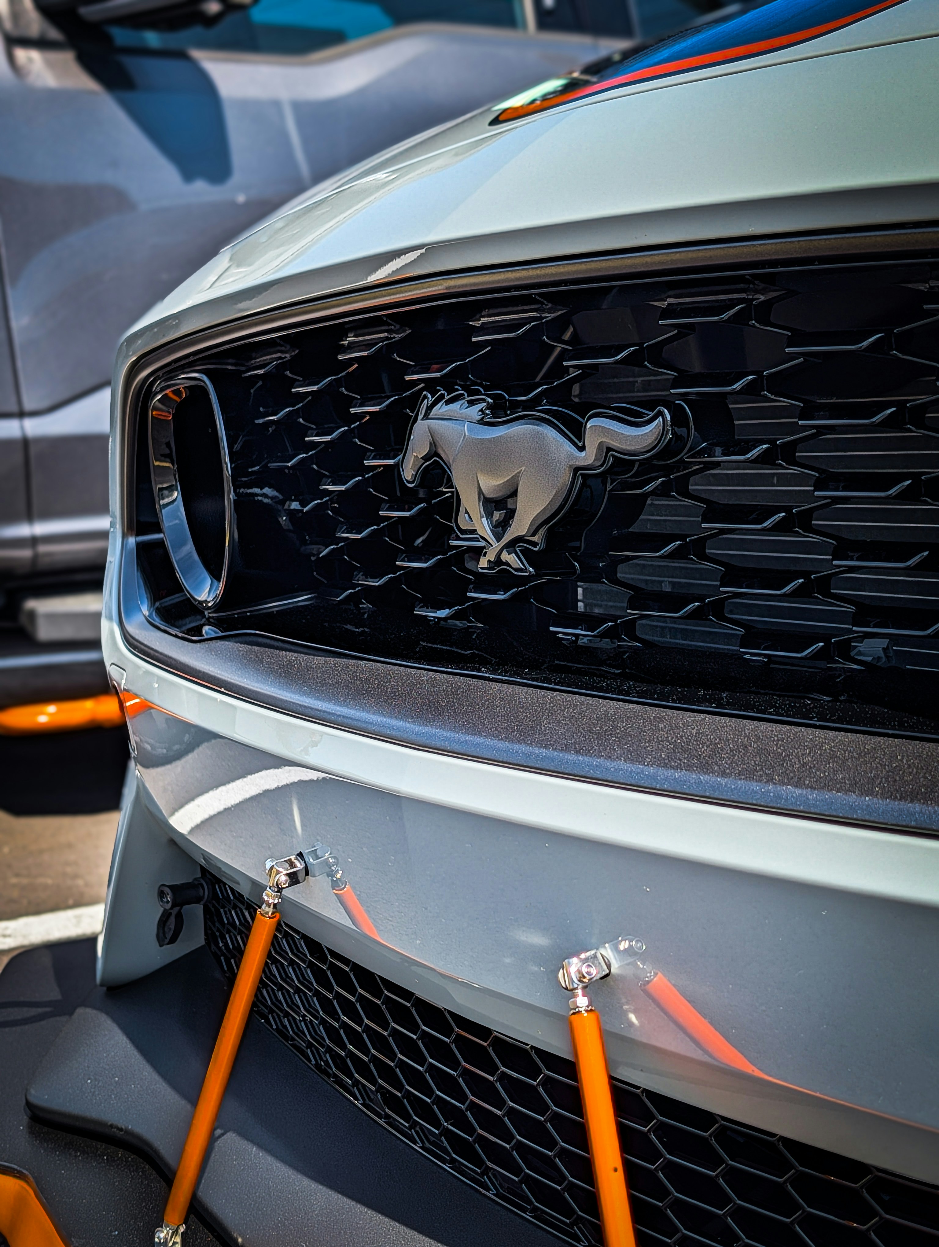 Close-up of a white ford mustang grille with horse emblem.