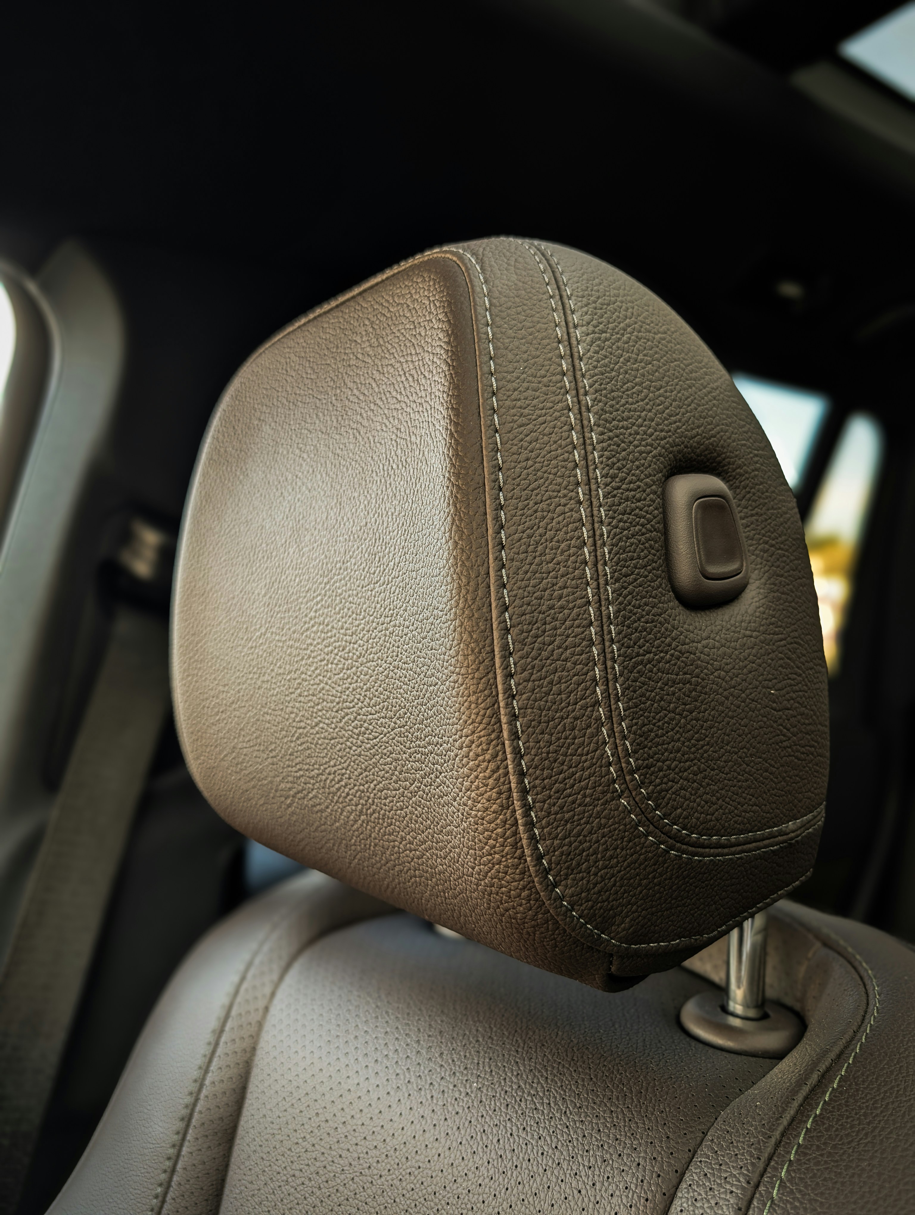 Brown leather car seat headrest with stitching