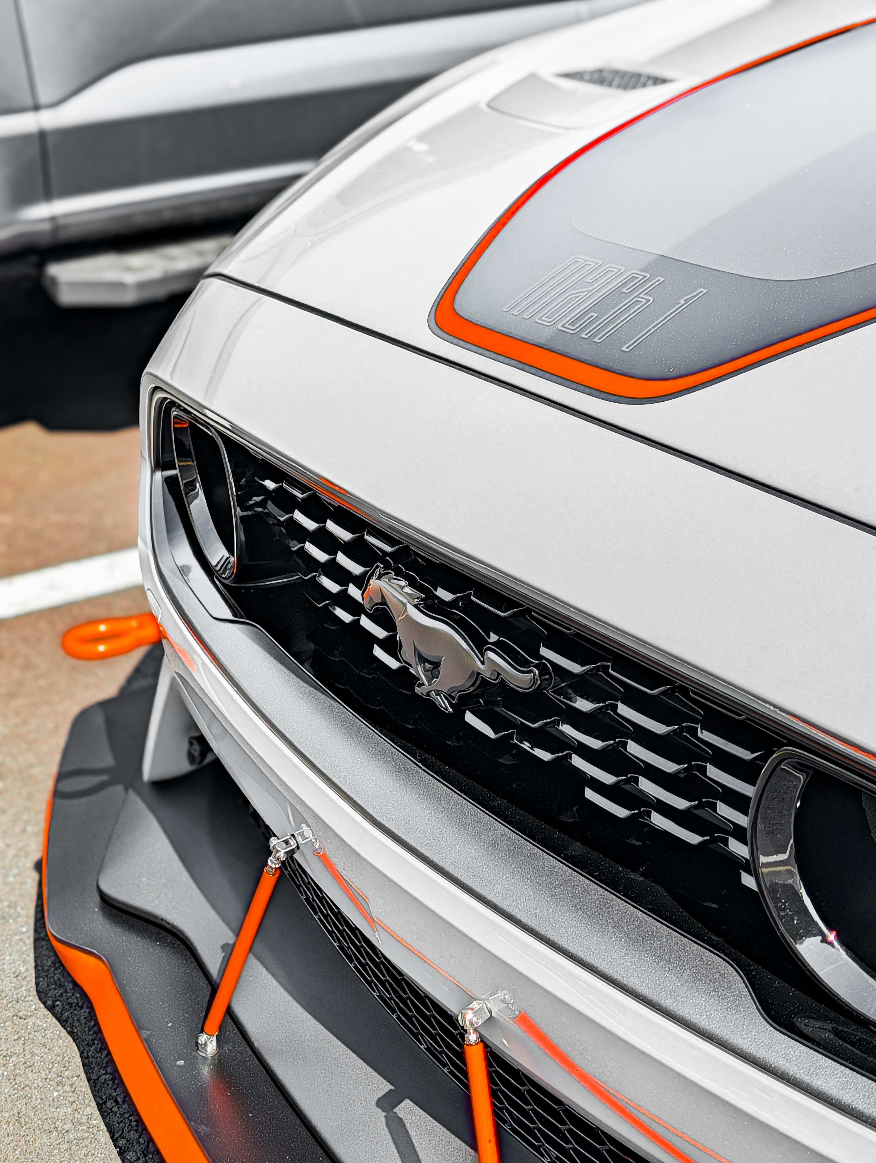 White sports car with orange accents and horse emblem