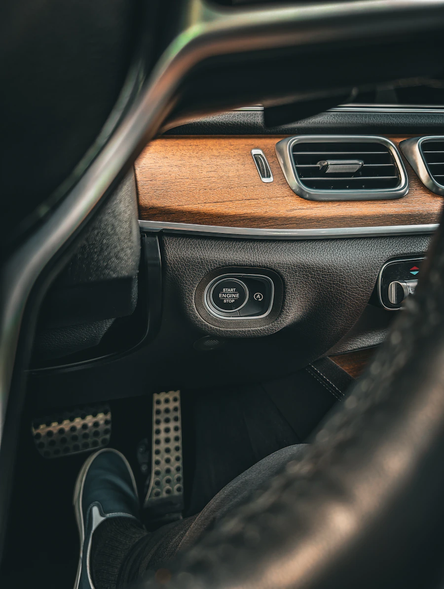 Wood trim dashboard with a start engine stop button and alloy pedals below, all dust free.