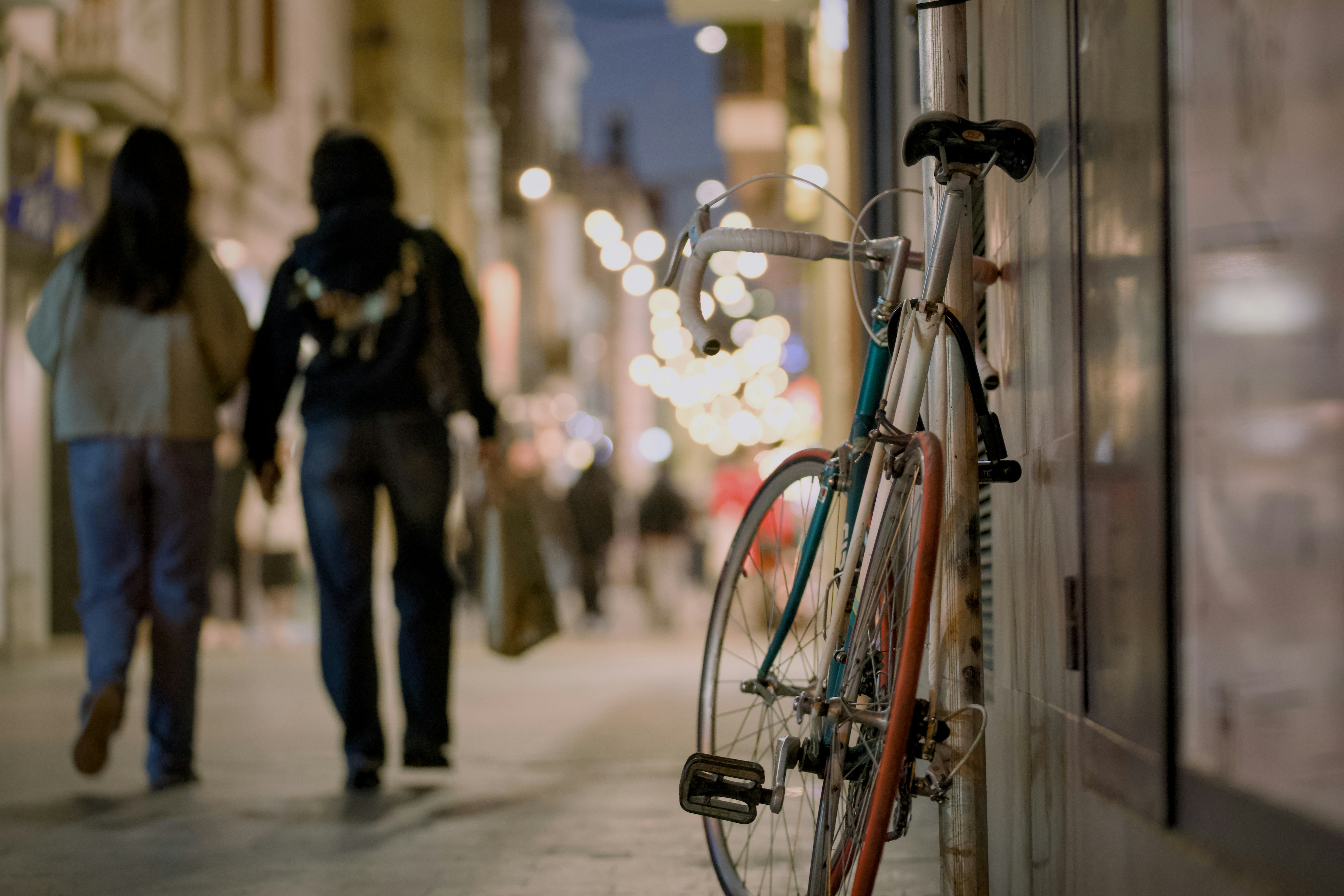 Dos personas caminan por una calle de noche.