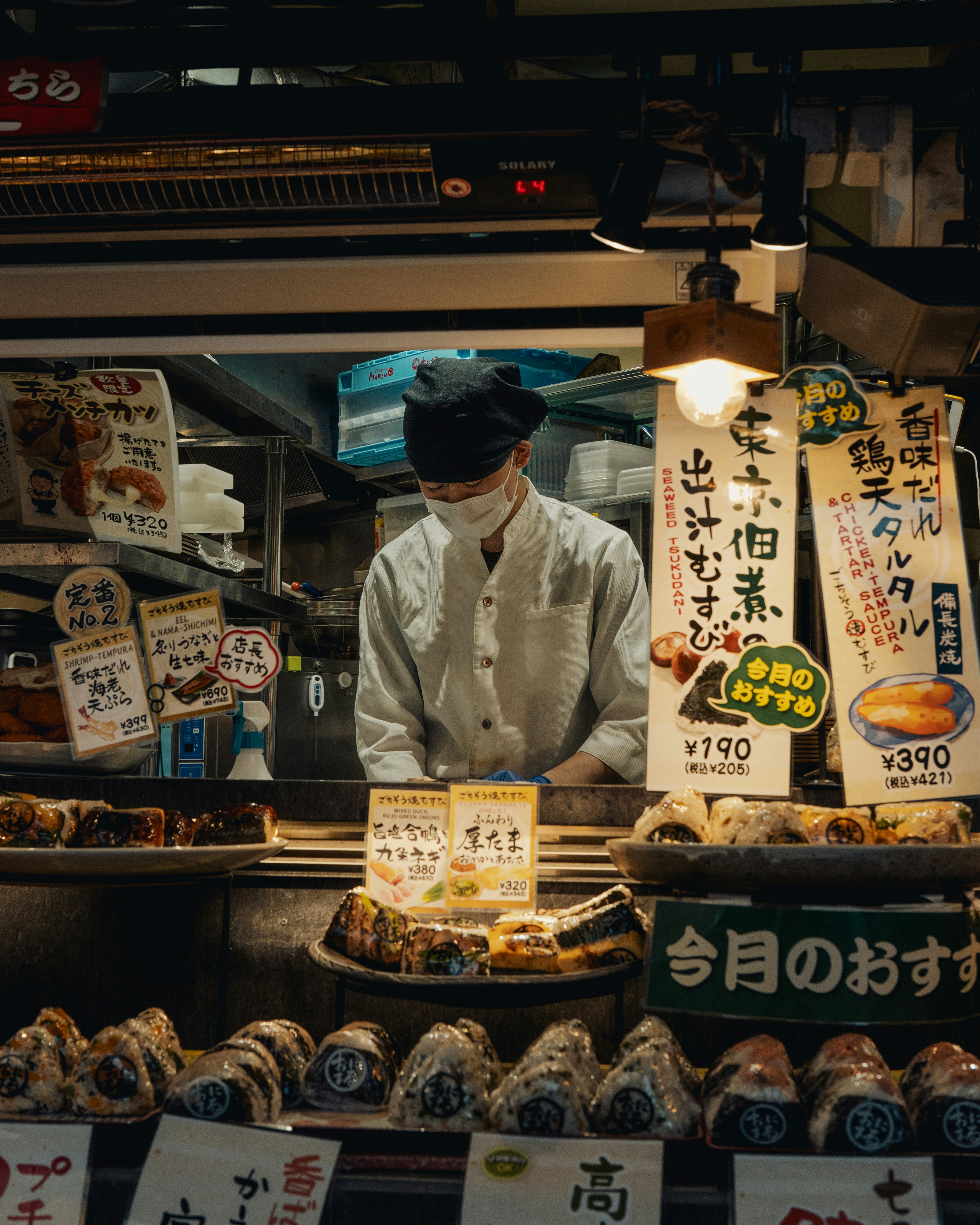 Un vendeur masqué prépare la nourriture à un stand de marché japonais.