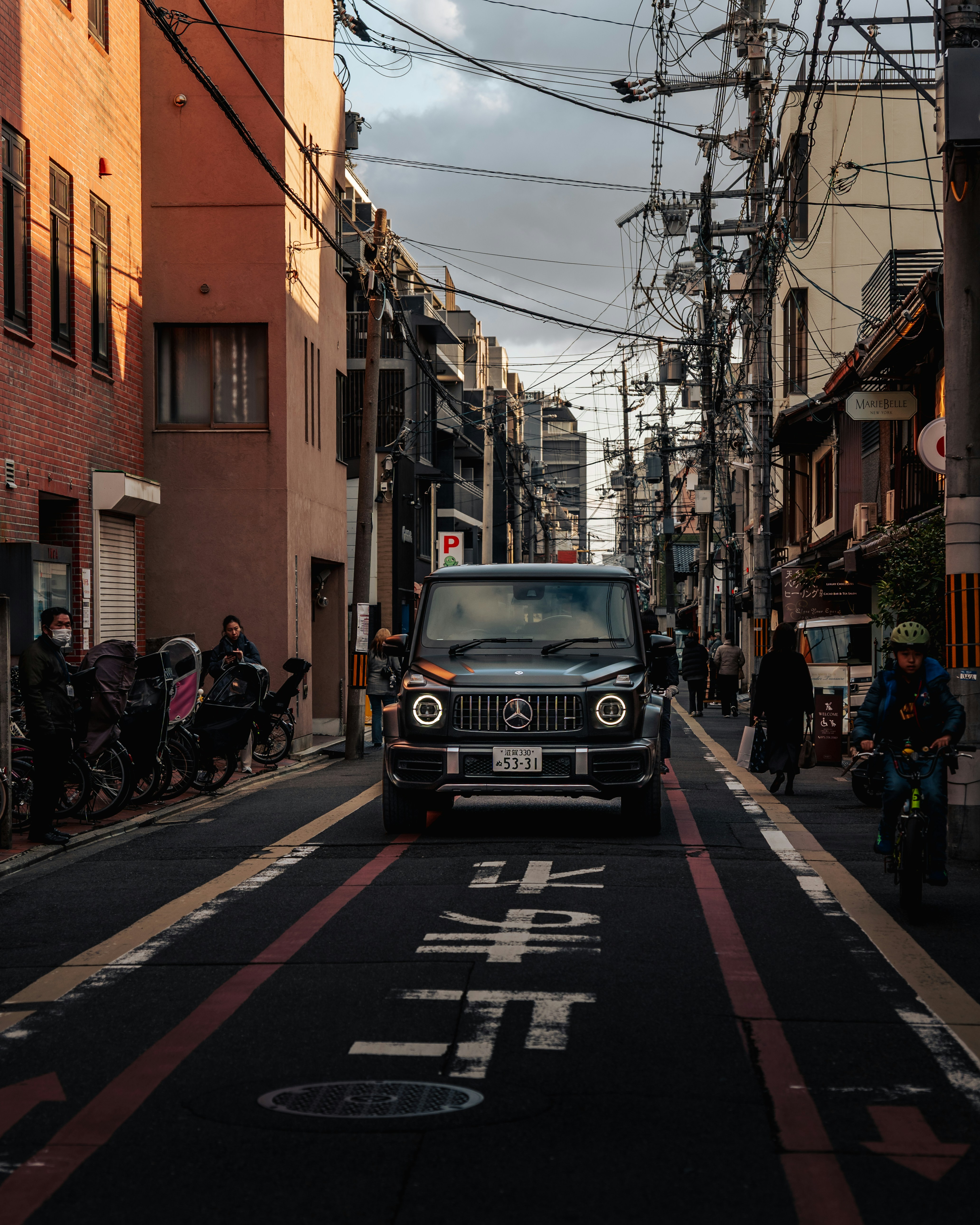 Une Mercedes noire G-wagon descend une rue étroite de la ville