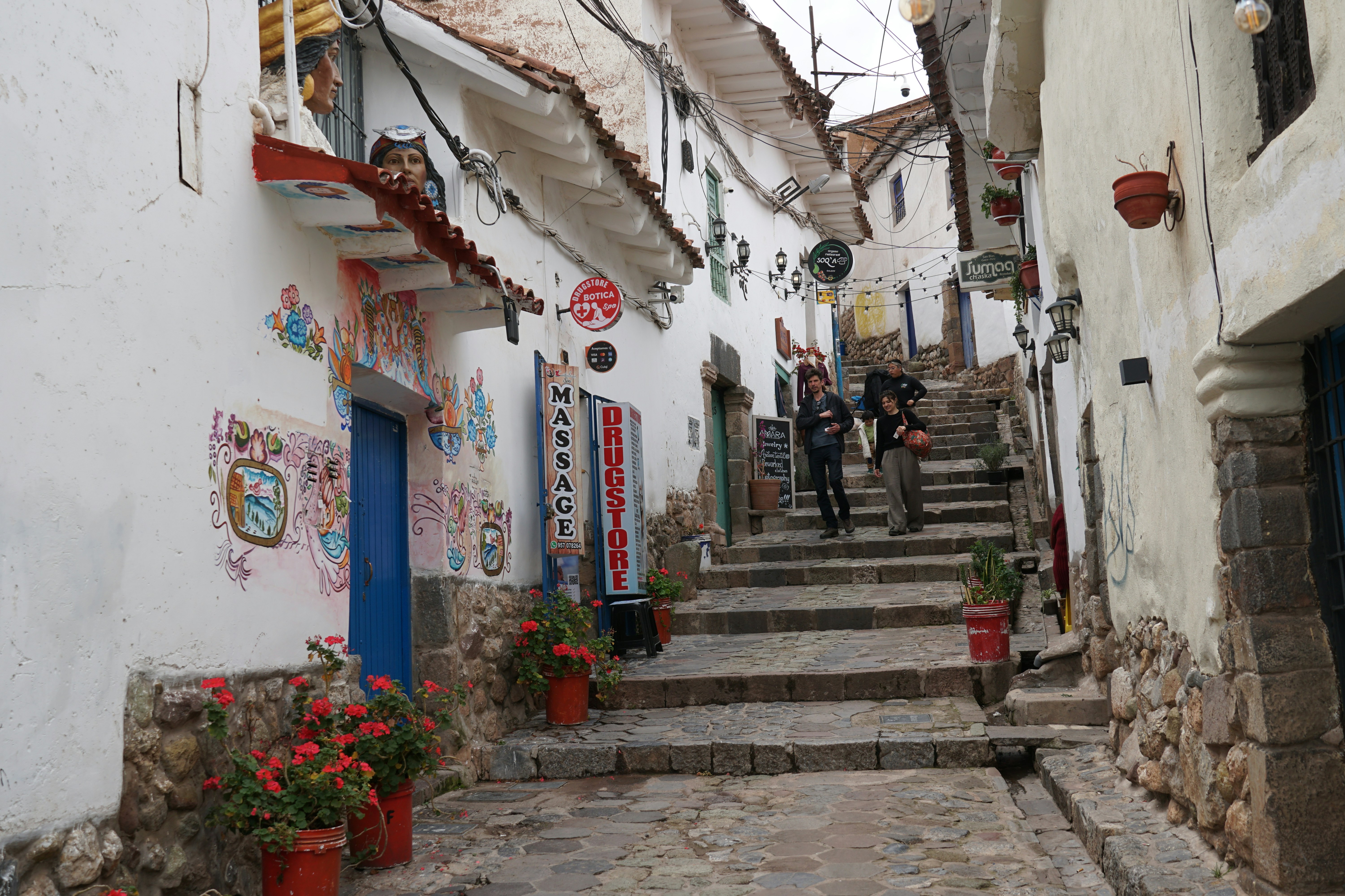 Two people walk up a narrow, stone street.