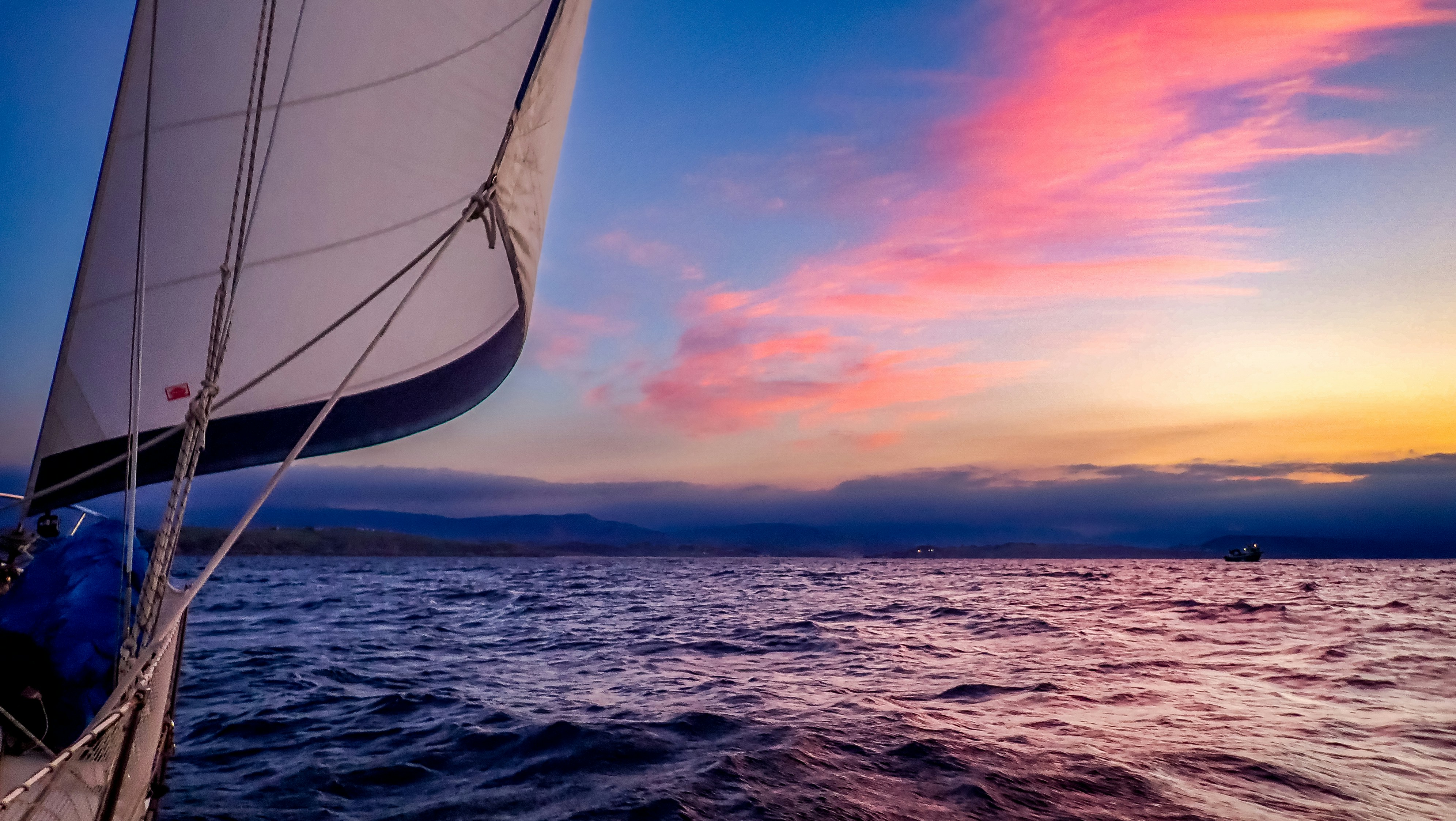 Sailboat on the ocean at sunset with colorful sky