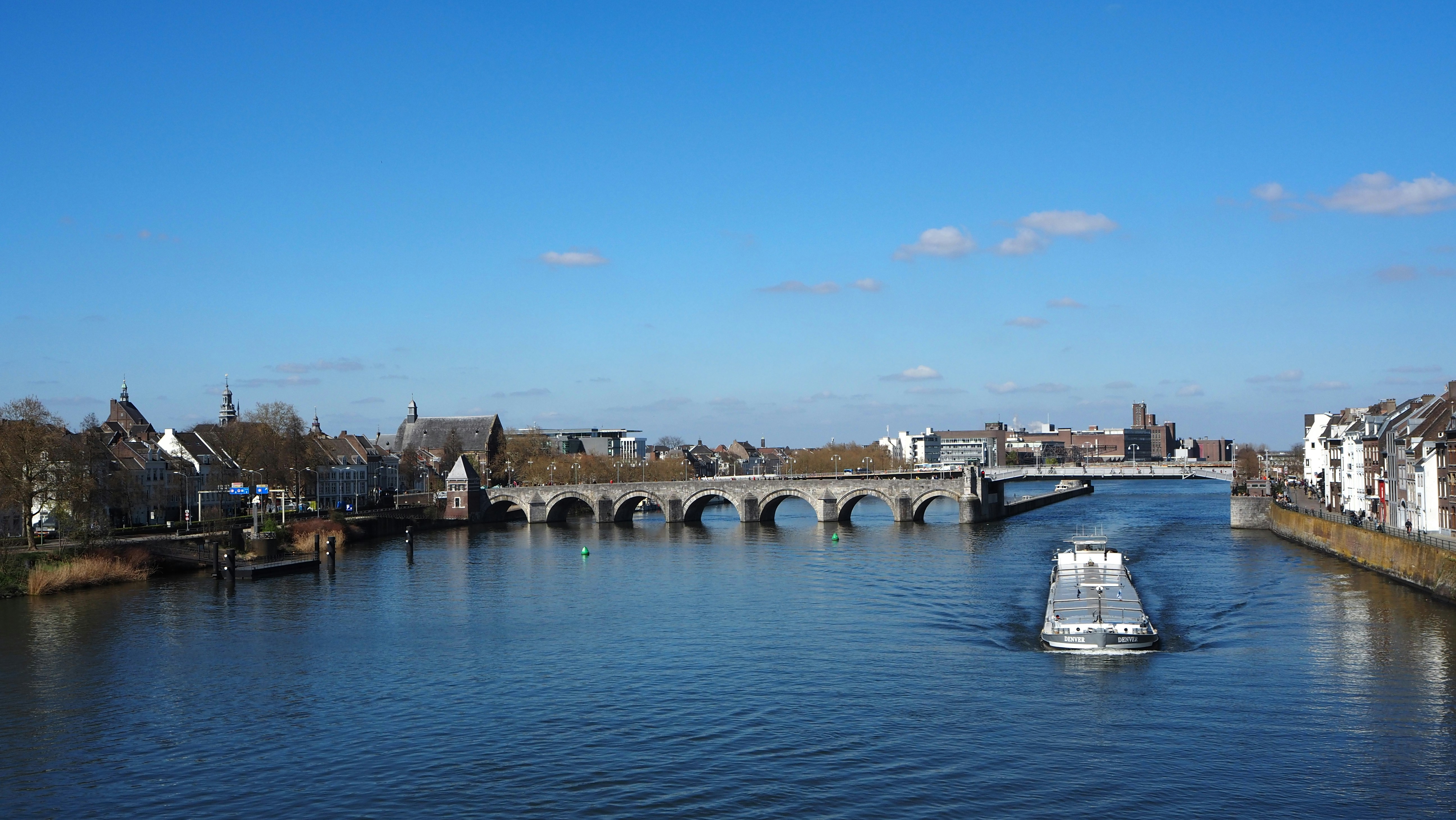 Boat on river passing under a stone bridge.