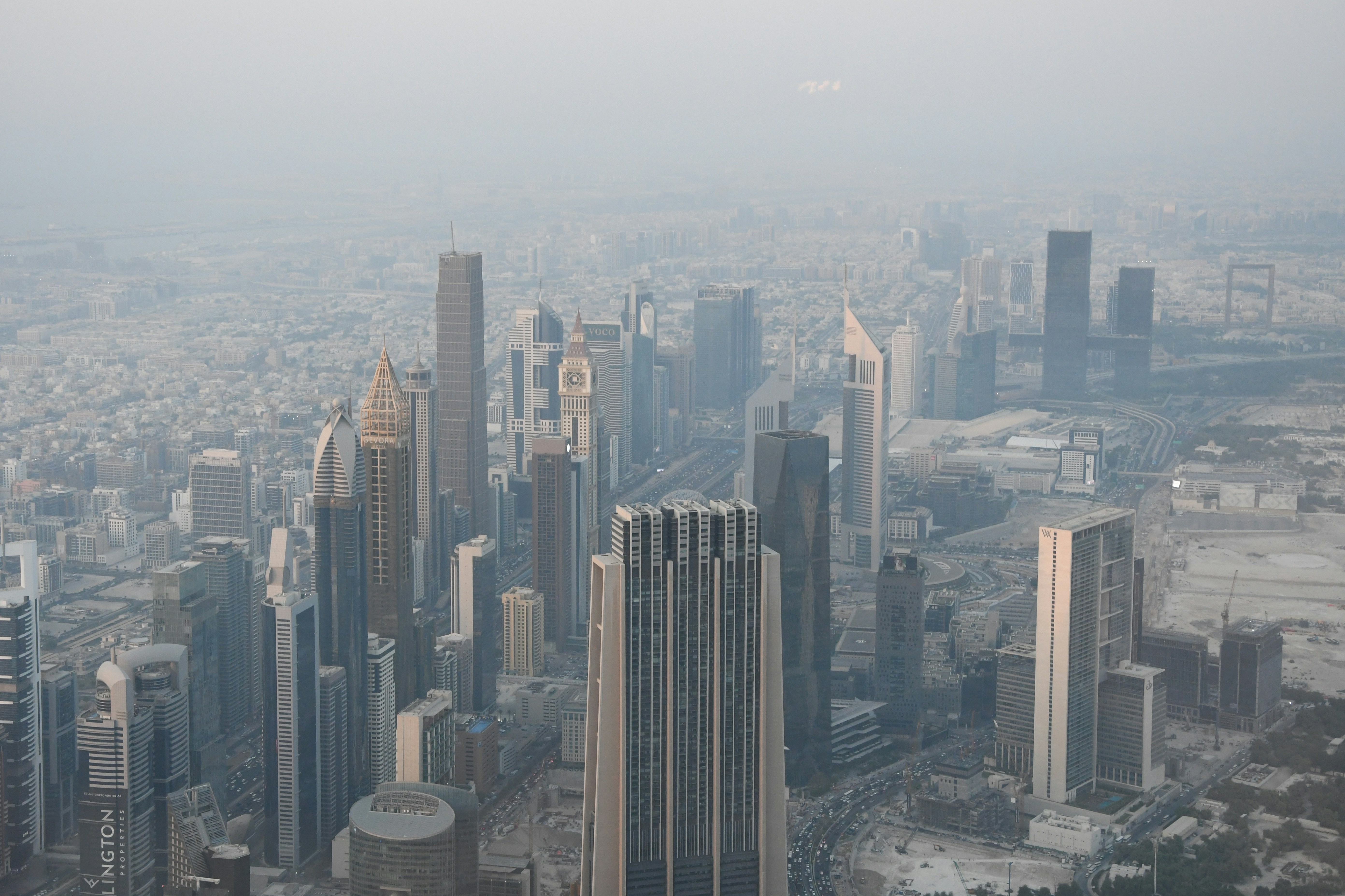 Skyscrapers and hotels of Dubai in the desert haze, and the Dubai Frame in the distance.
