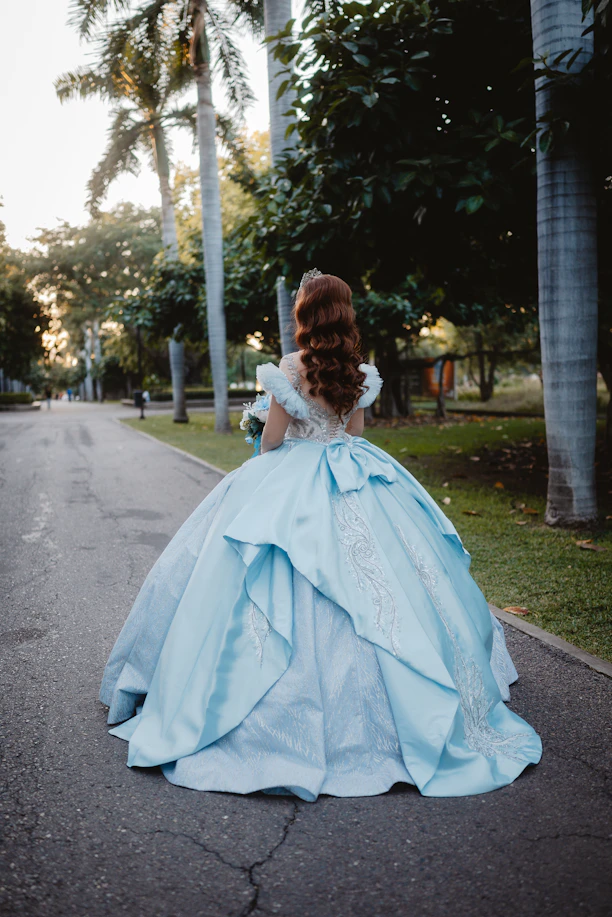 Woman in a blue ballgown walking in a park