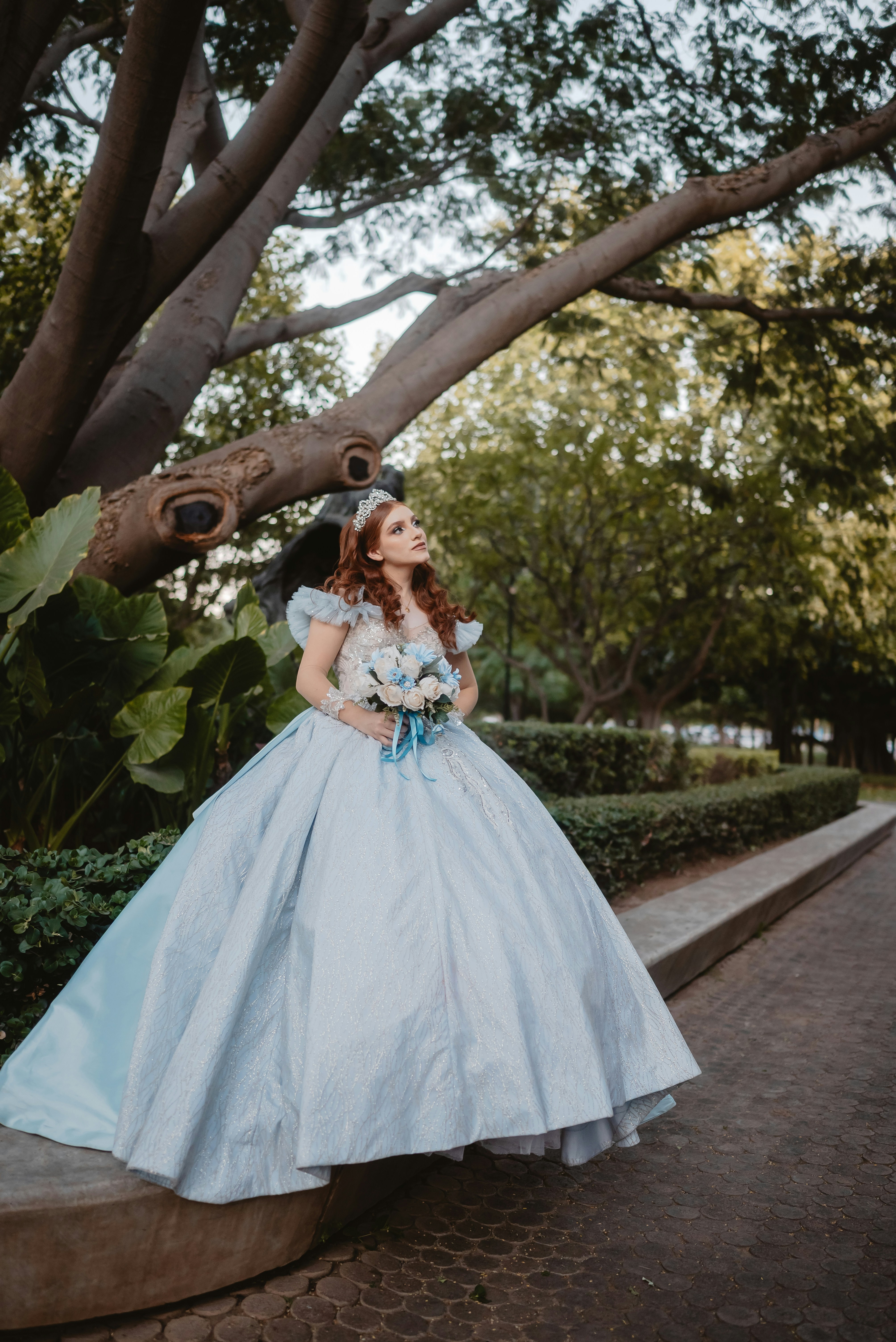 Jeune femme en robe de bal bleu clair tenant des fleurs