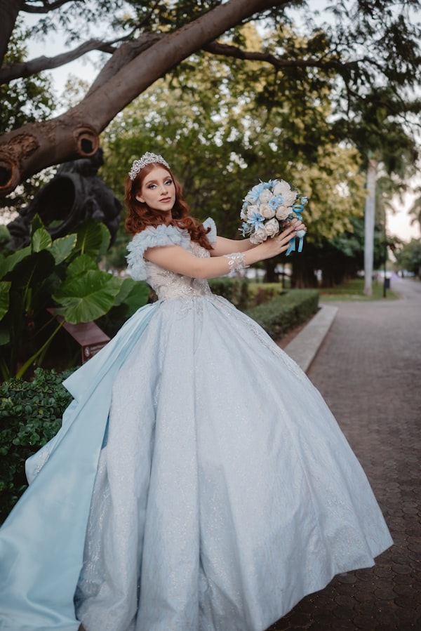 Regina Sofía caminando por un sendero de jardín con su ramo de flores azul y blanco