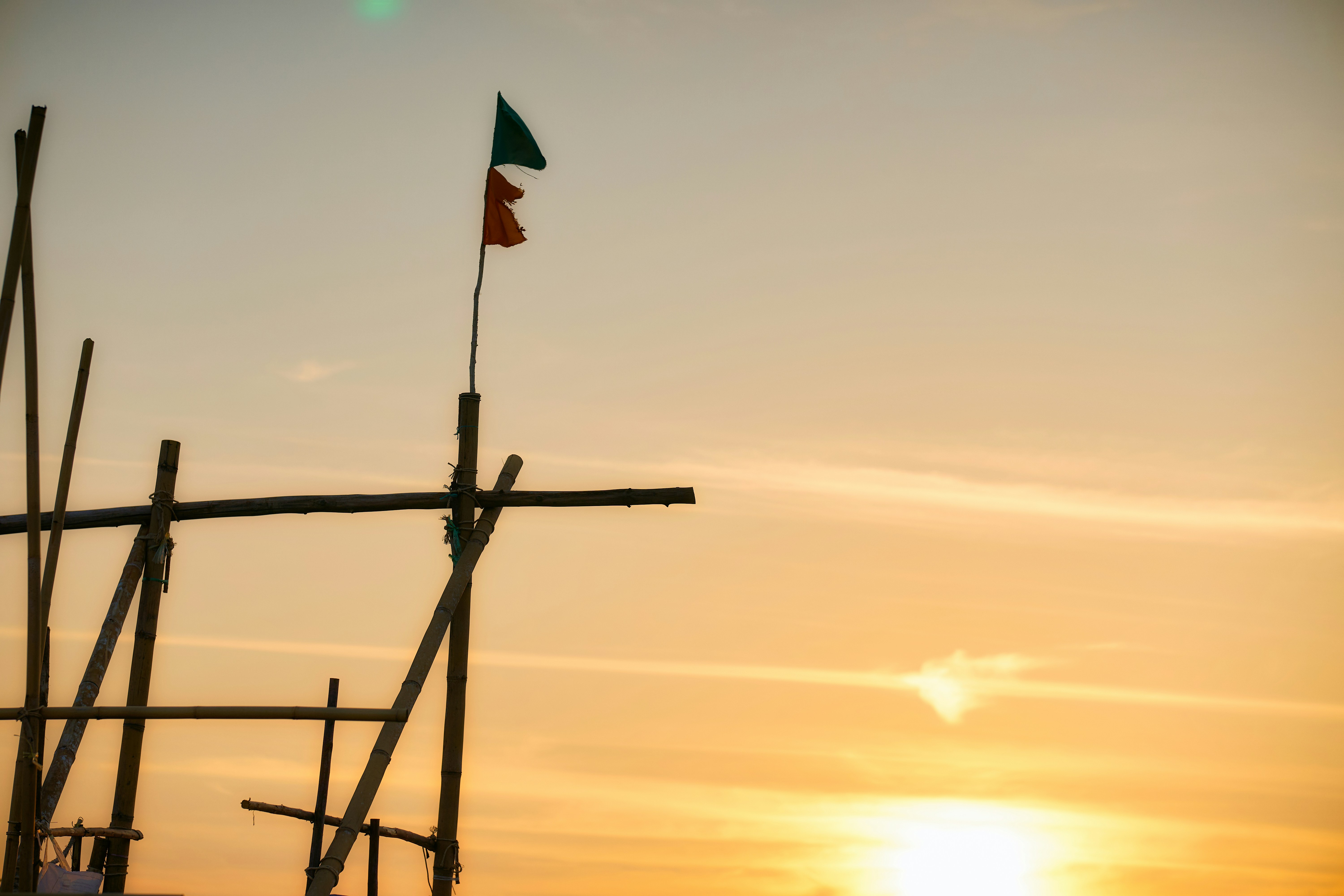 Wooden structure with flags against sunset sky