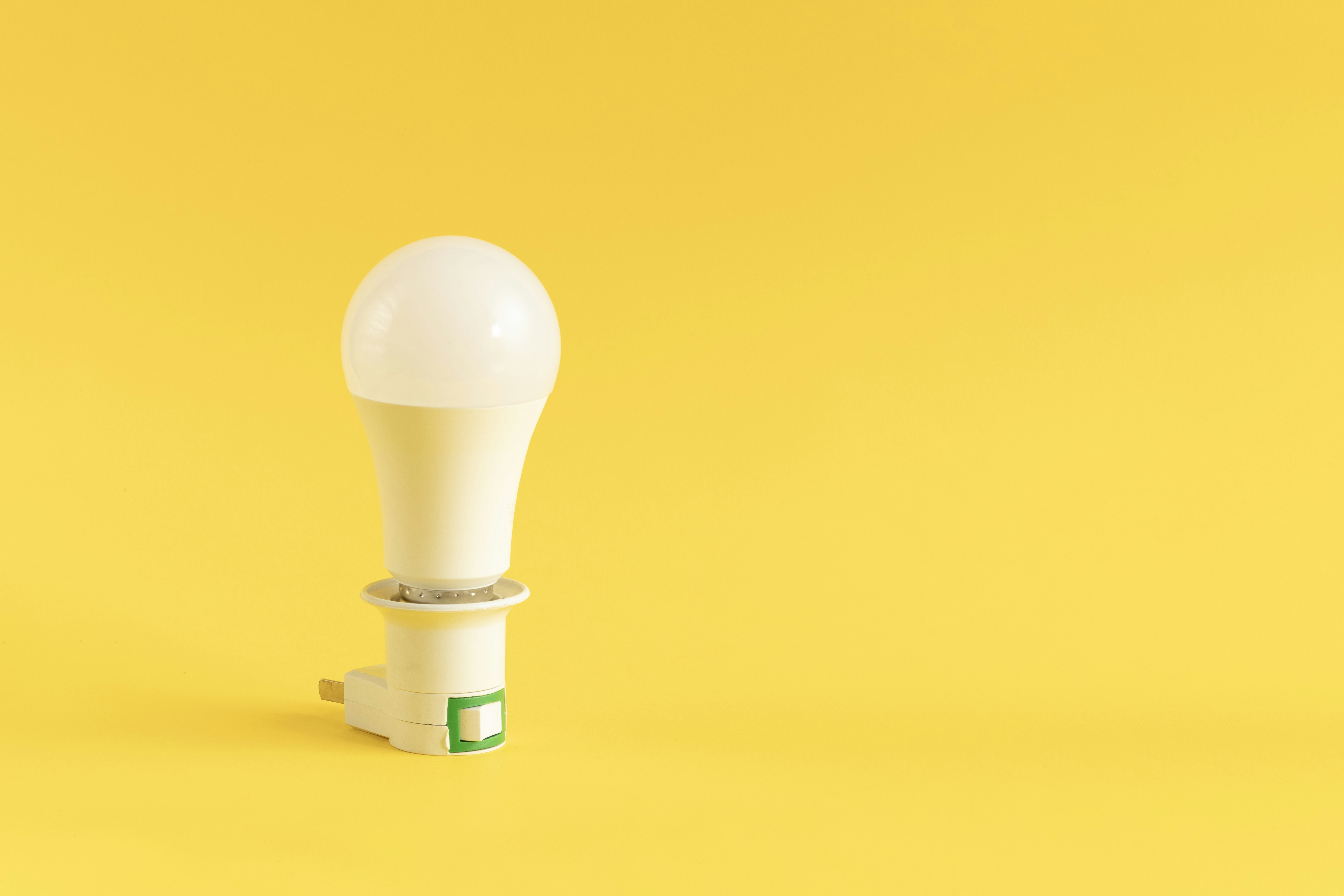A white led light bulb on a yellow background