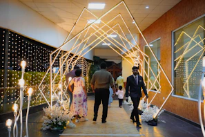People walk through a glowing geometric archway at an event.