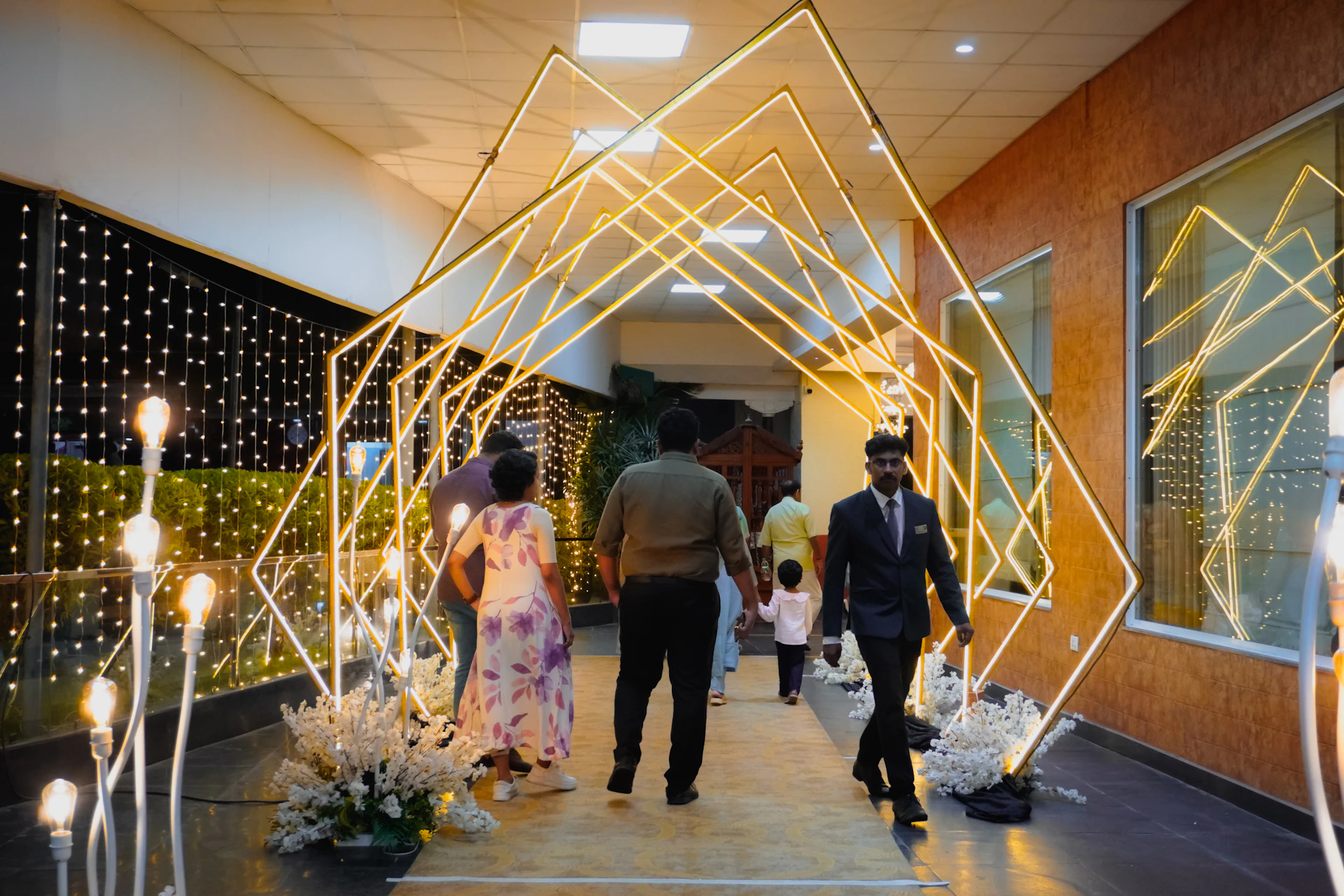 People walk through a glowing geometric archway at an event.