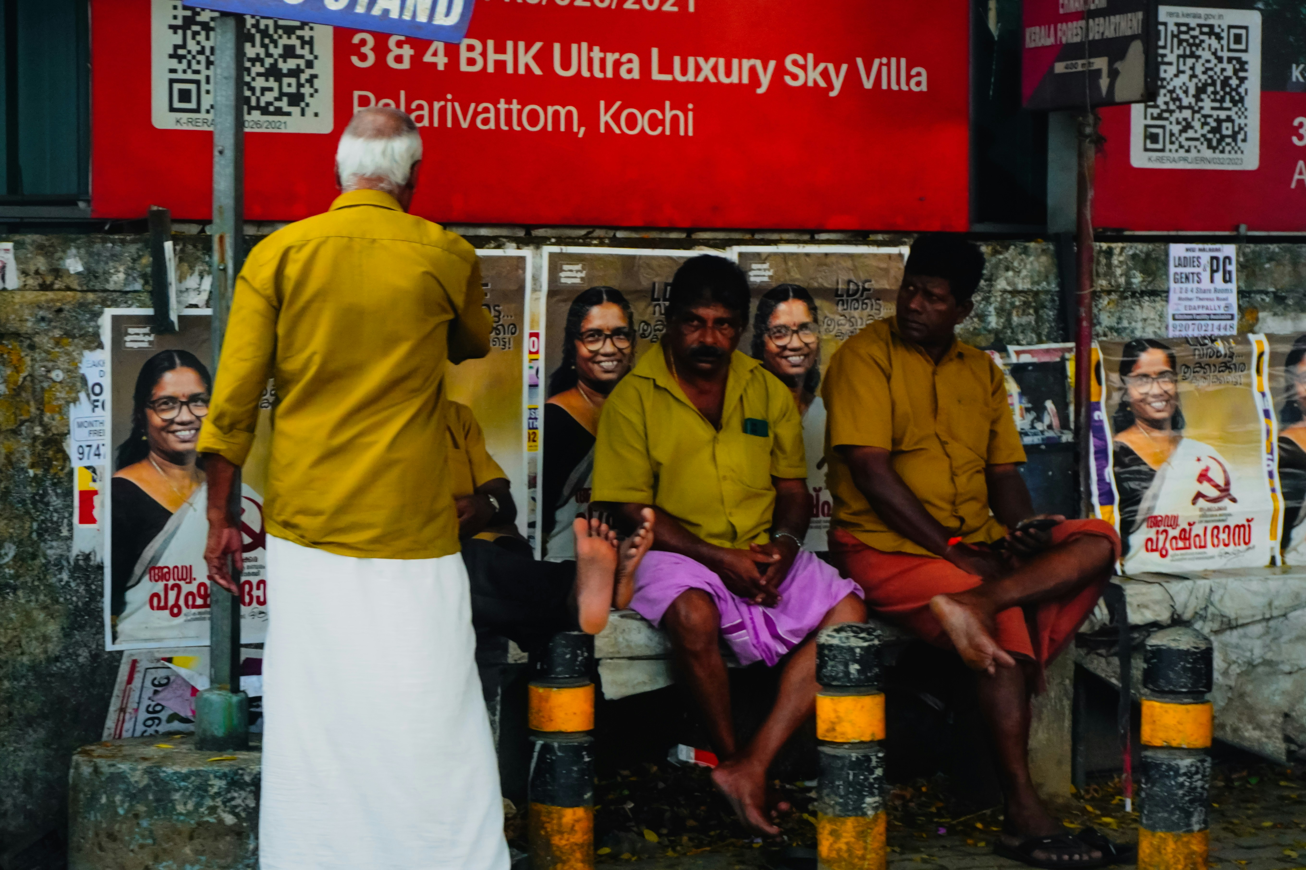 A bustling bus stand in Kerala with many women commuters, some smiling, waiting for a bus, reflecting optimism and accessibility.
