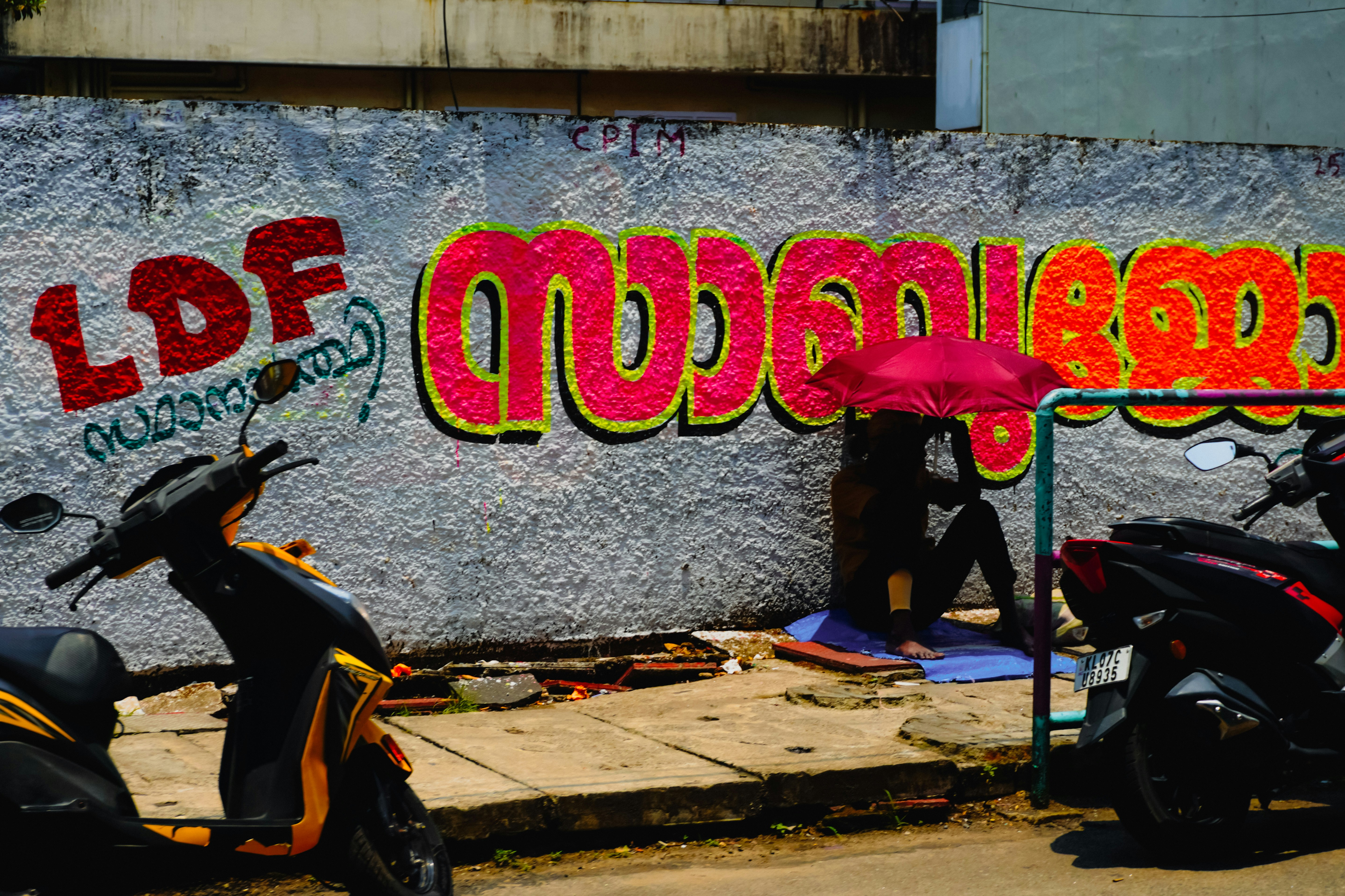 Grafiti di dinding dengan orang-orang dan skuter terdekat skuter di dekatnya