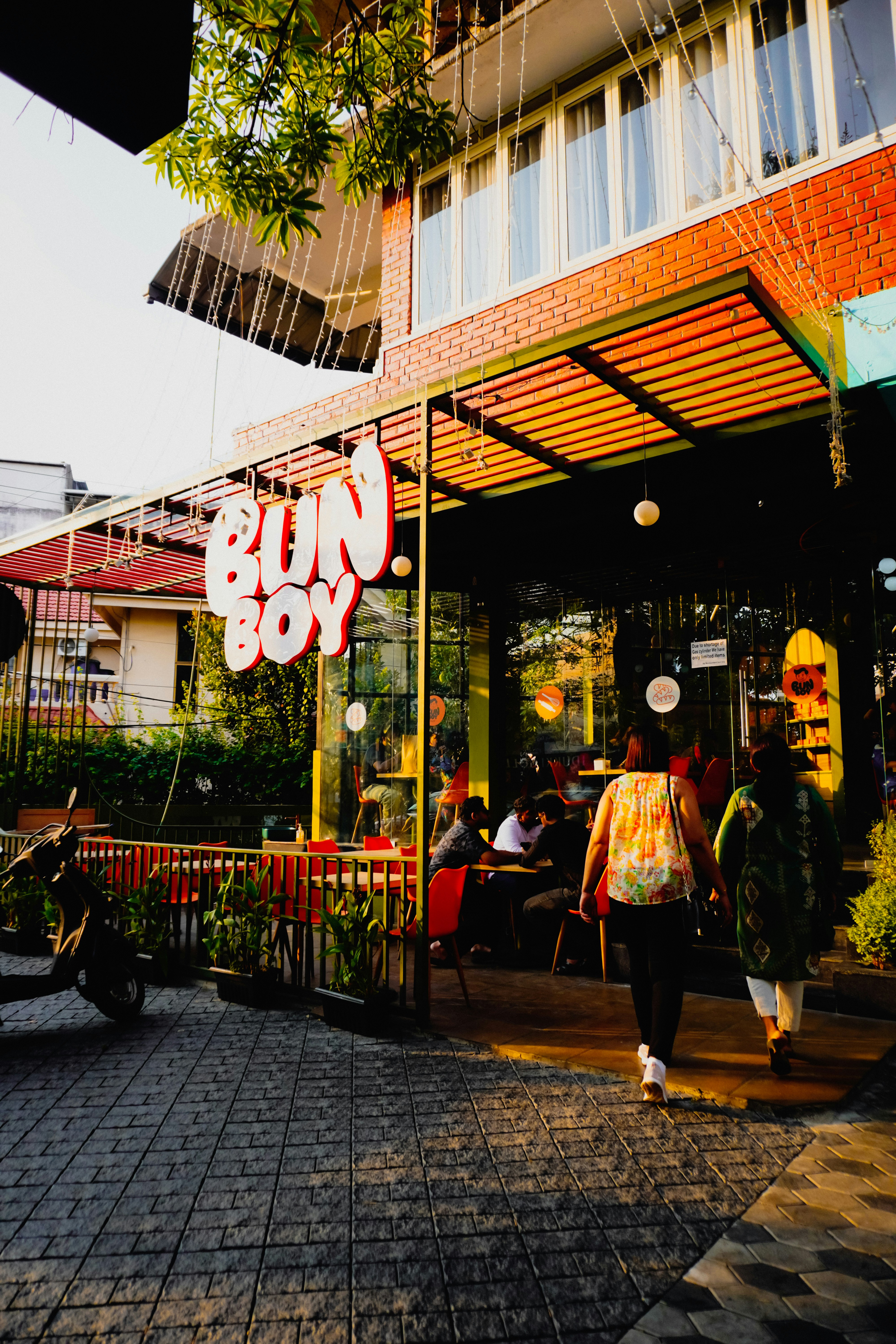 Orang-orang berjalan menuju sebuah kafe dengan tanda "bun boy".