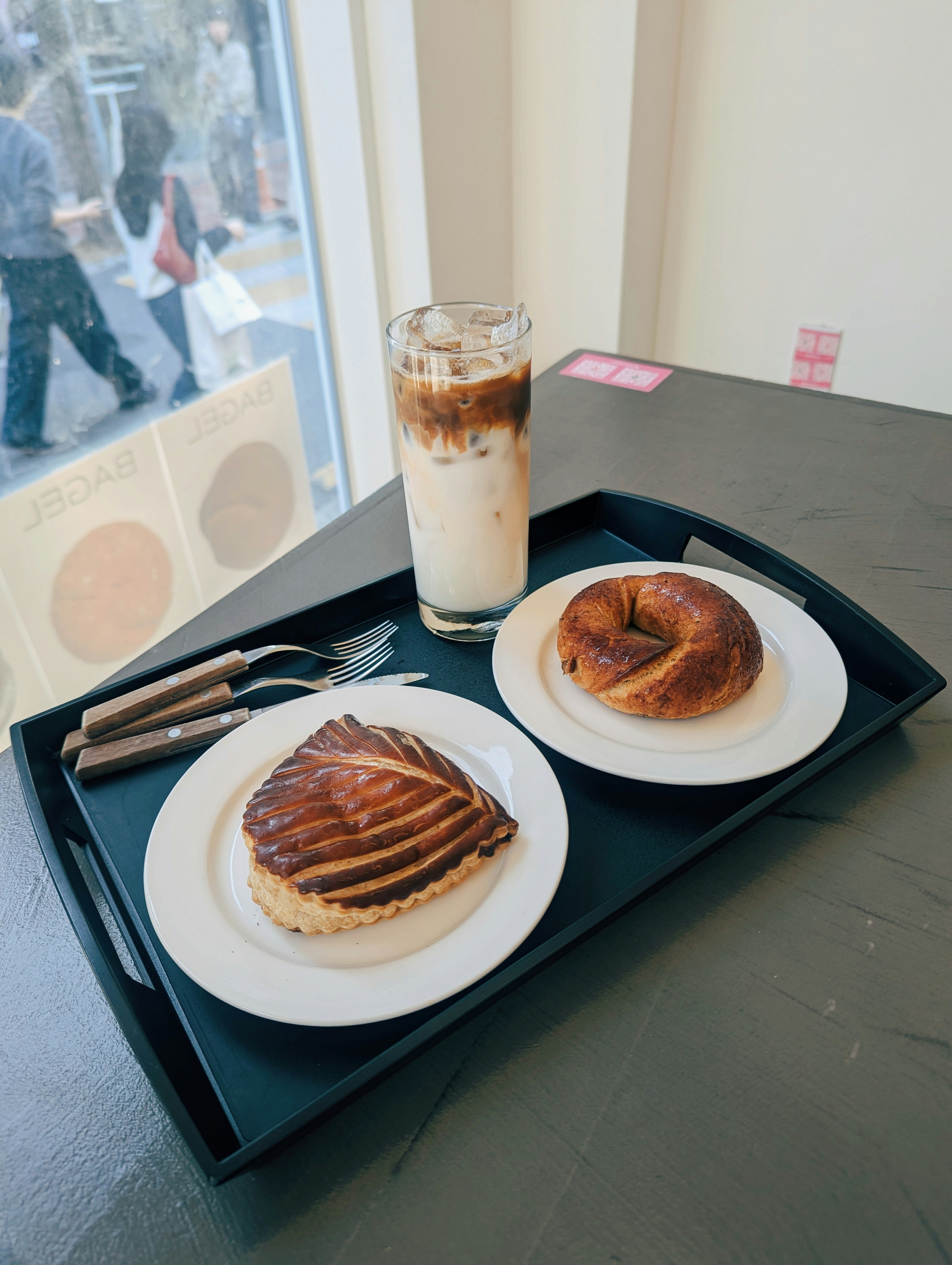 Café helado con masa y bagel en bandeja