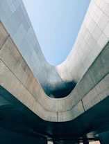 Curving concrete and metal architecture under a clear sky