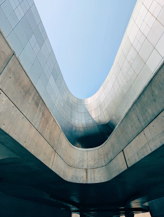 Curving concrete and metal architecture under a clear sky